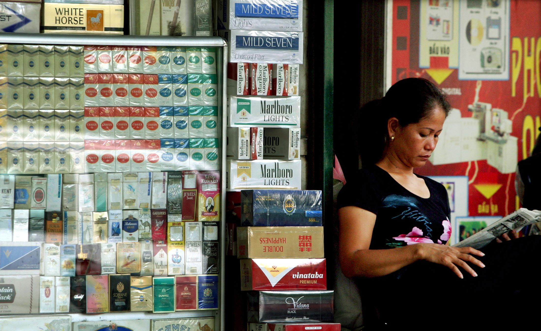 A Vietnamese vendor reads a newspaper while she displays cigarettes for sale, in Hanoi, Vietnam, on July 8, 2005.
