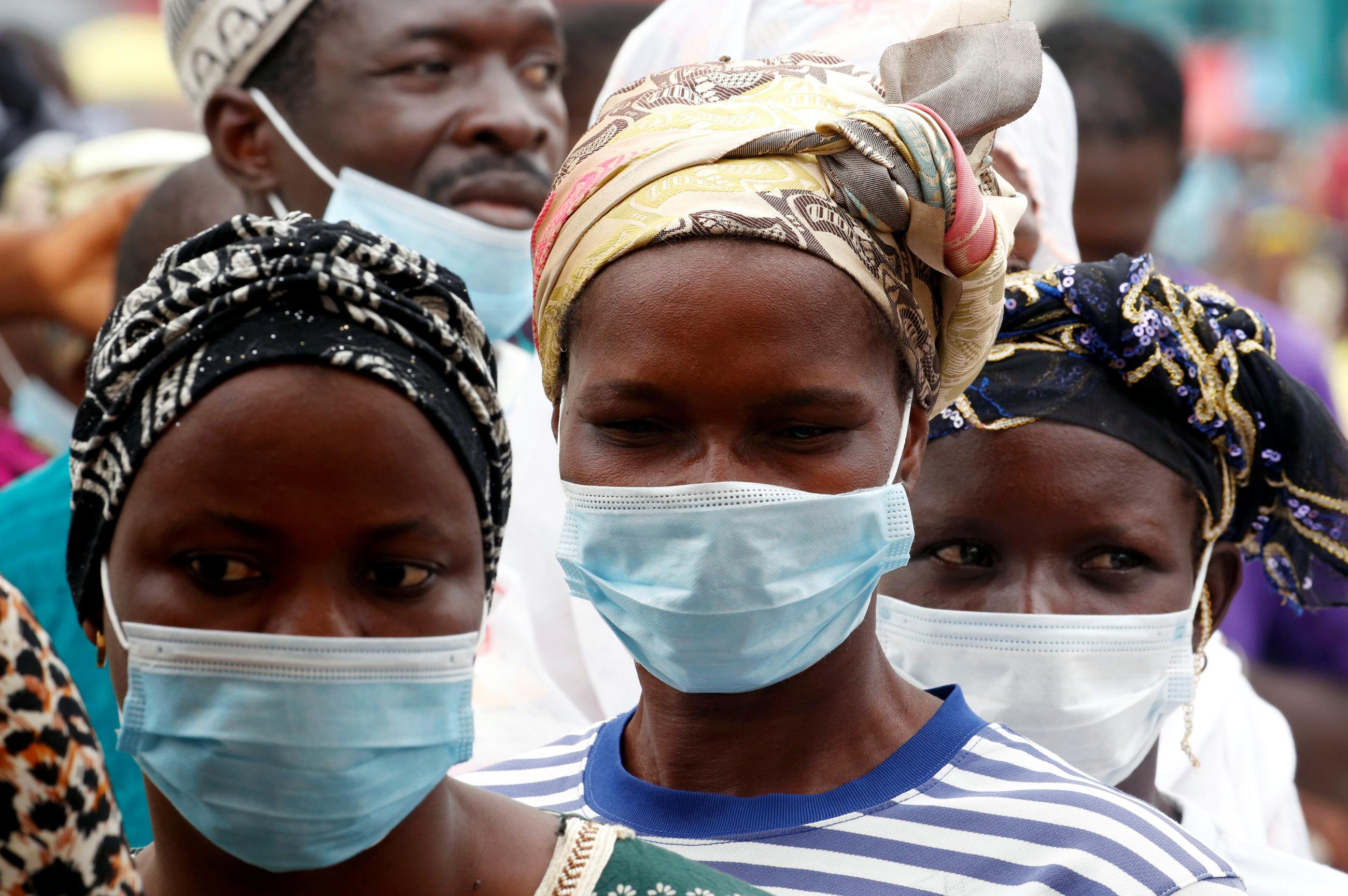 People wearing face masks wait in line to receive a COVID-19 vaccine near a mobile vaccination truck during a prevention campaign, in Abidjan, Ivory Coast, on August 6, 2021.