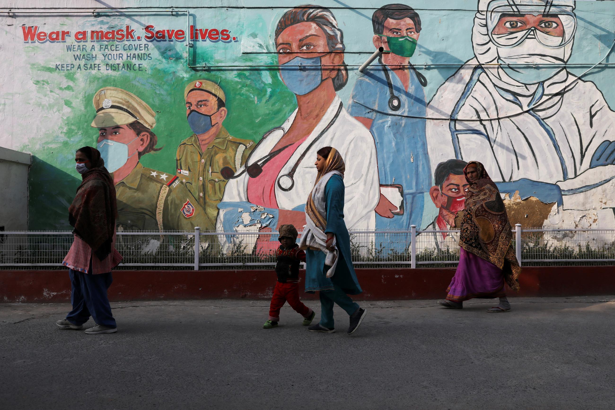 Women walk past a mural, in New Delhi, India, on February 7, 2022. 