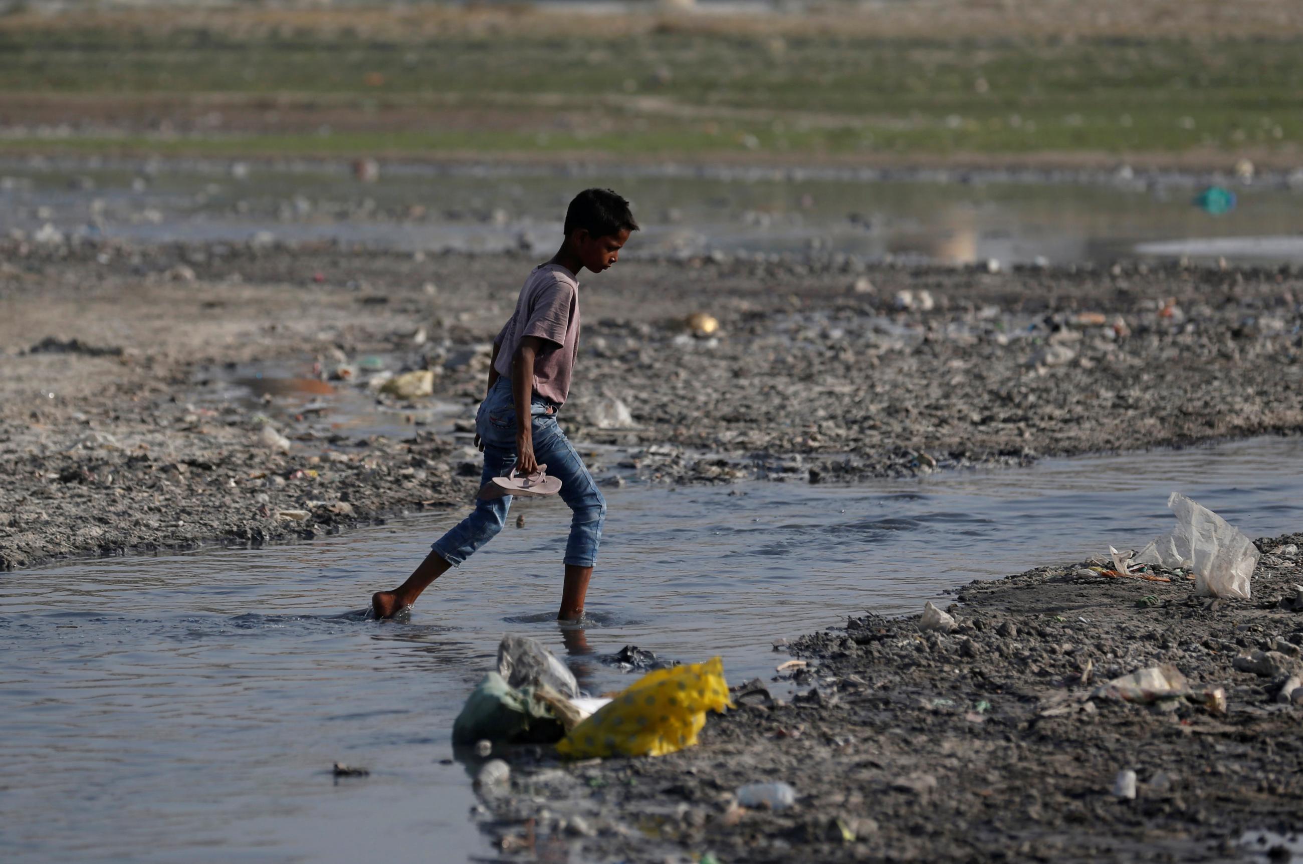 A boy crosses a drain on the banks of the Ganges River, in Kanpur, India, on April 4, 2017.
