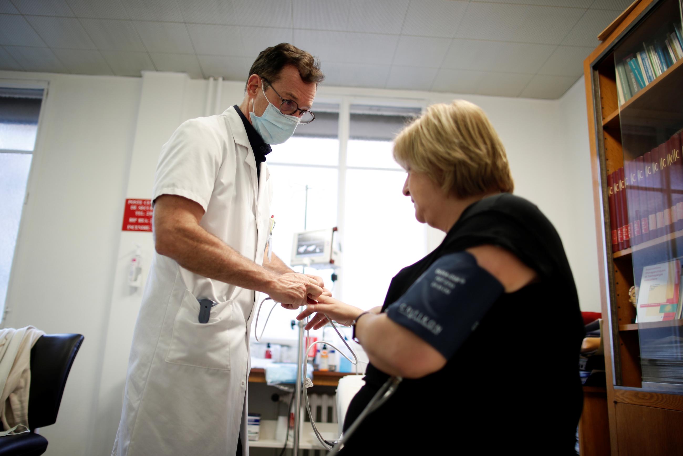 Doctor Nicolas Barizien examines a patient who has been suffering from COVID-19 symptoms for months, near Paris, France, on December 8, 2020. 