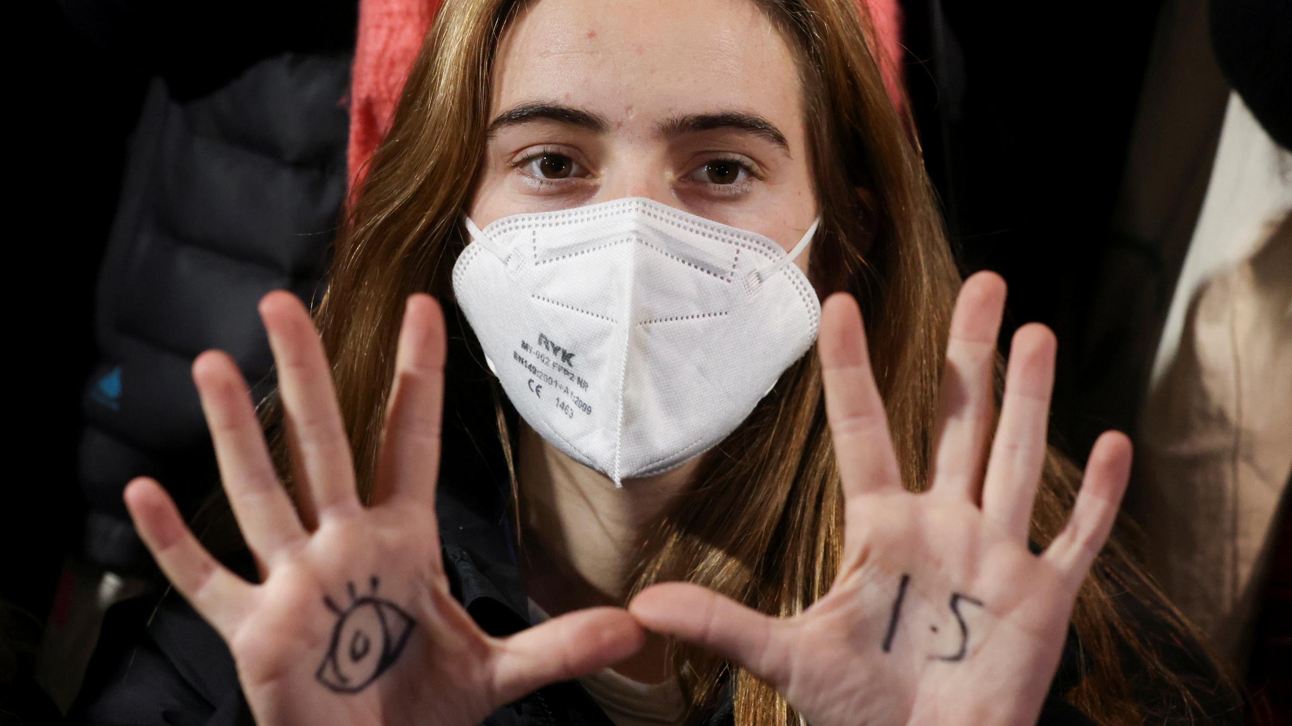 Climate activist Adelaide Charlier holds up her palms, which show a sketch of an eye and a 1.5