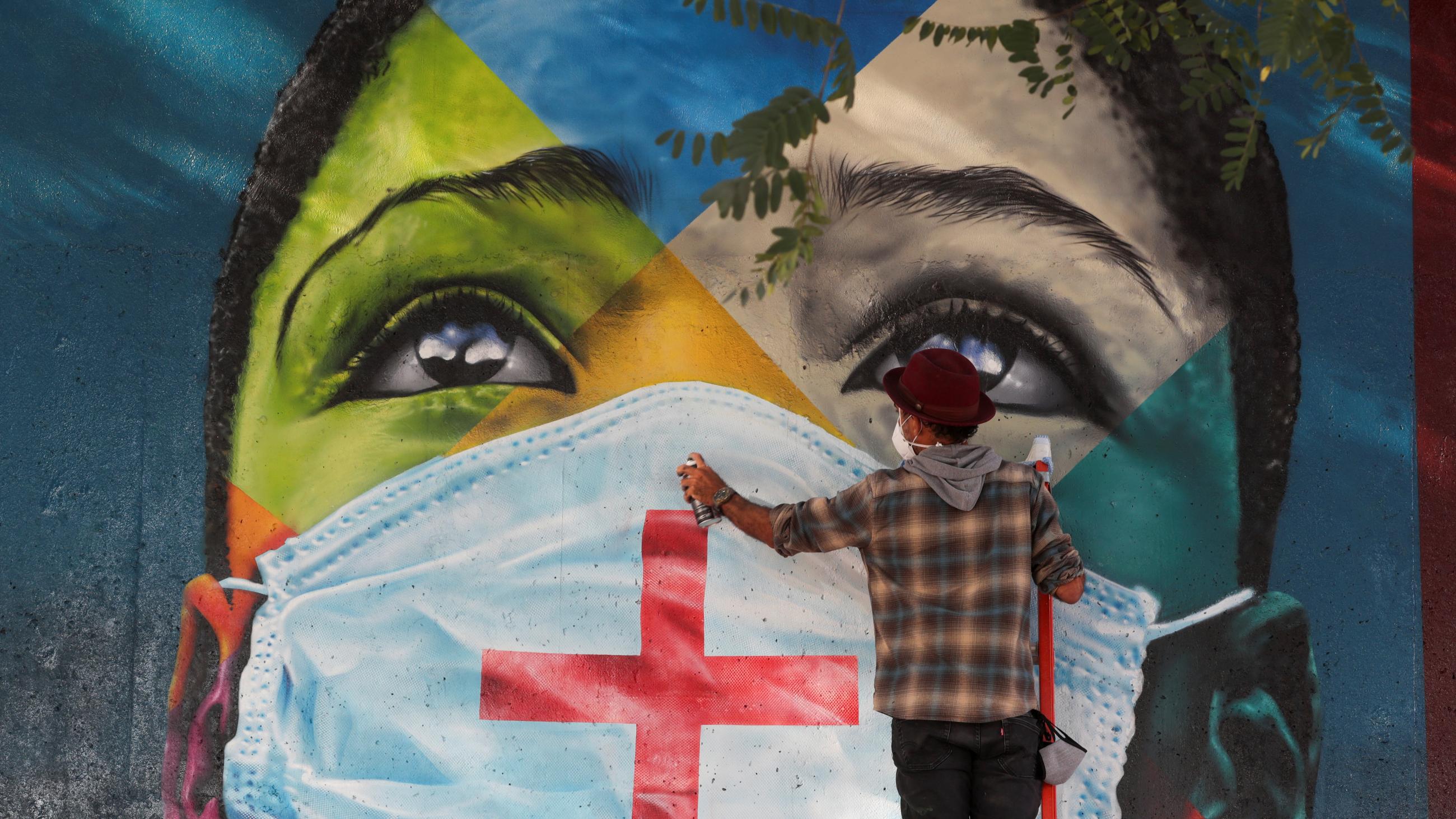 Brazilian graffiti artist Eduardo Kobra puts the final touches to his mural Coexistencia—Memorial da Fe por todas as vitimas do Covid-19, translated as Coexistence—Memorial of Faith for All Victims of Covid-19, which shows children of different religions wearing protective face masks, in Sao Paulo, Brazil, on May 5, 2021.