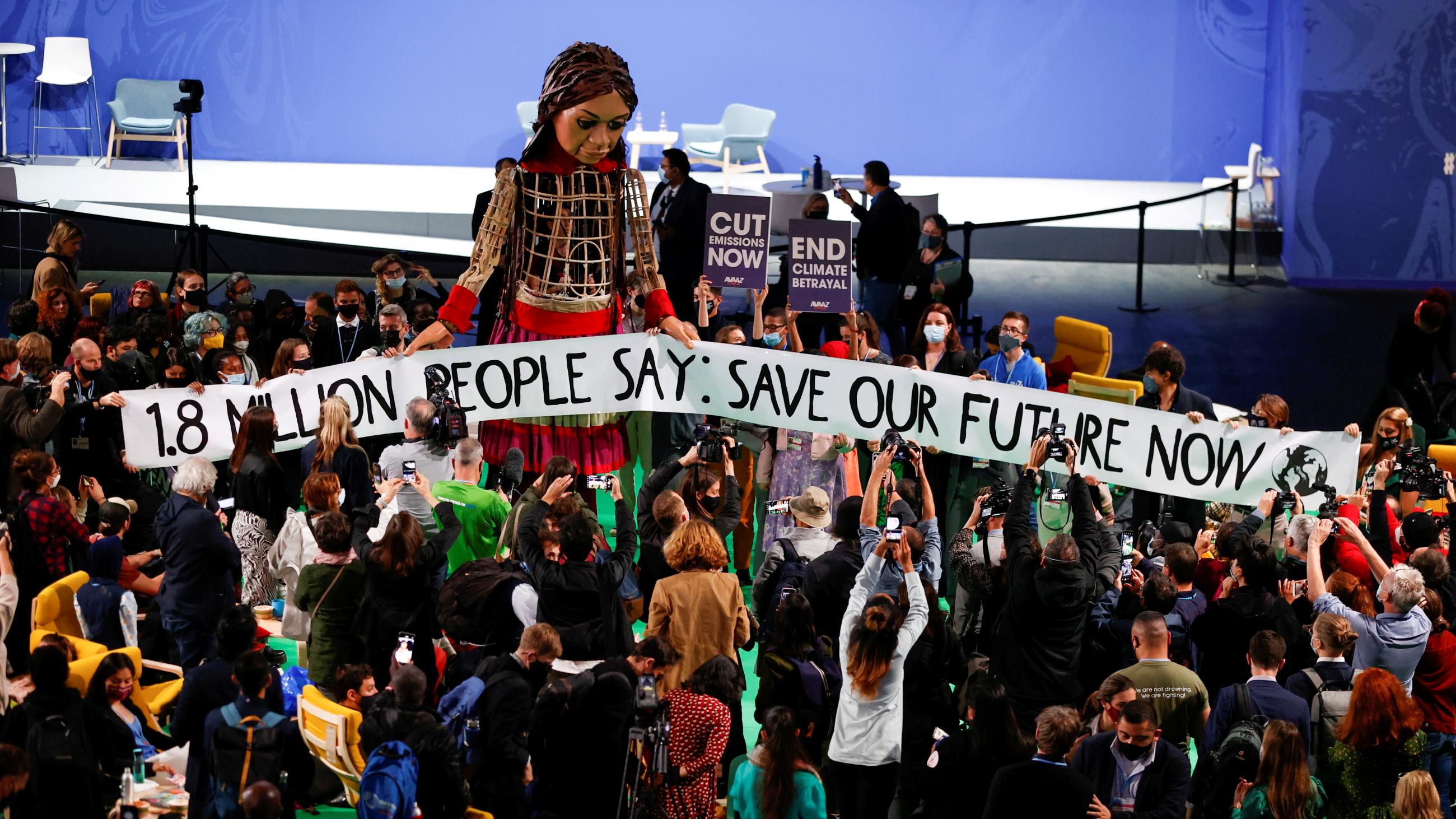 People gather around "Little Amal," a giant puppet of a young Syrian refugee girl at COP26