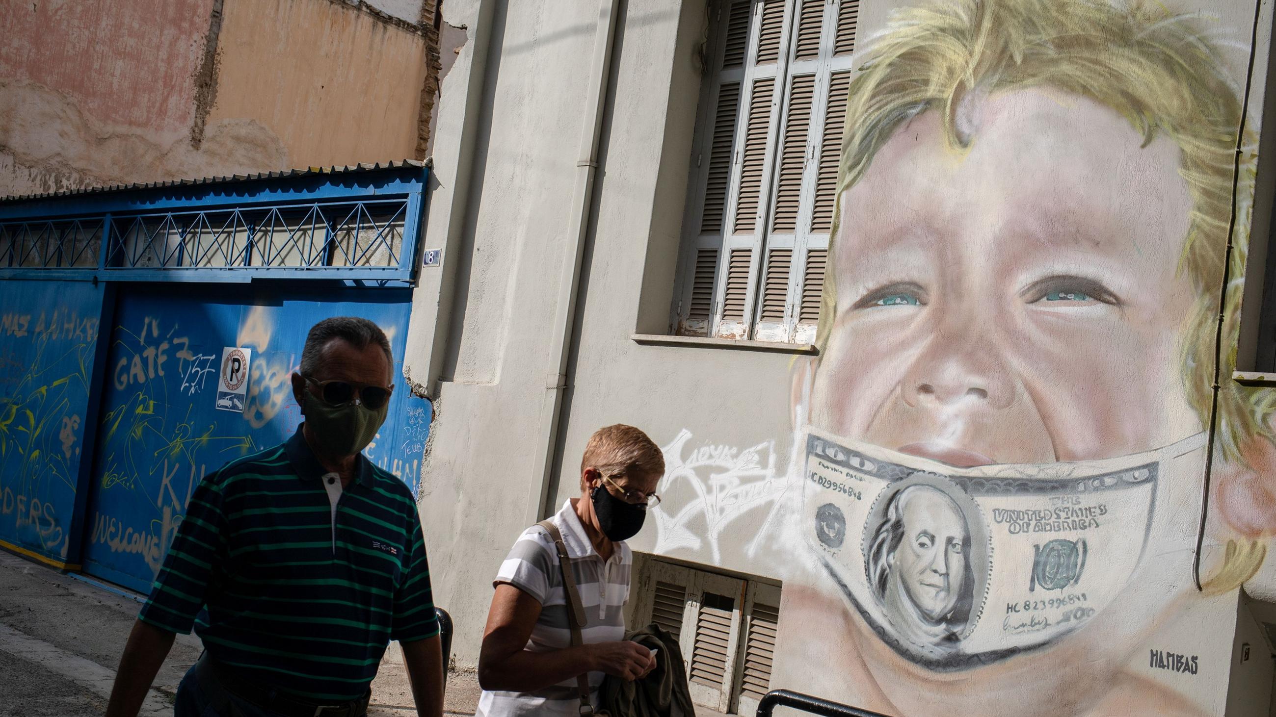 People walk past a work by Greek visual artist Hambas in Athens, Greece, on October 27, 2020.