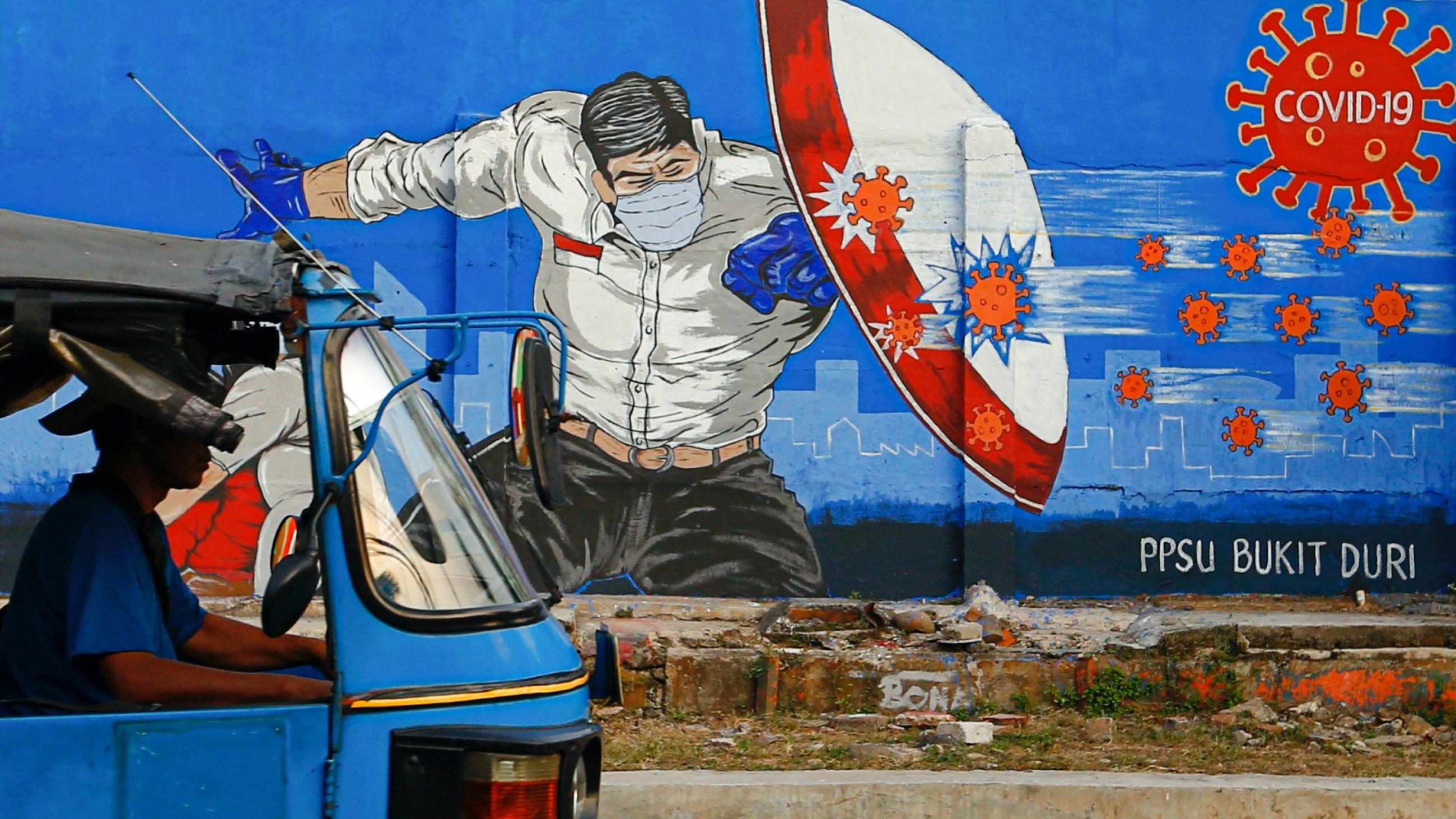 A rickshaw taxi passes a mural promoting COVID awareness in Jakarta, Indonesia, on August 31, 2020.
