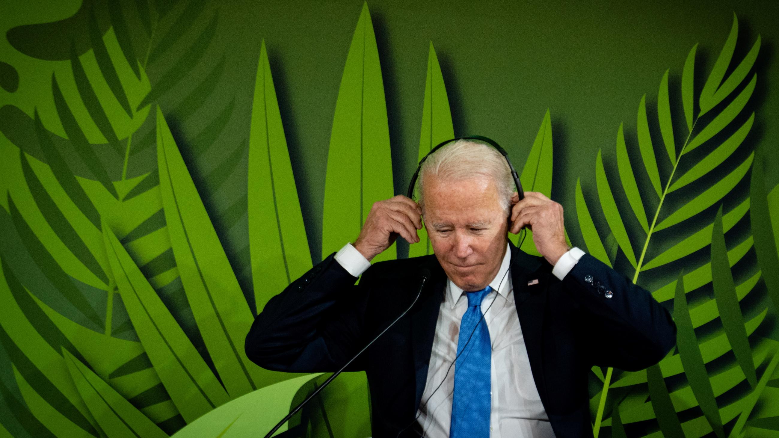 U.S. President Joe Biden puts on headphones to listen to speeches during the "Action on Forests and Land Use" event.