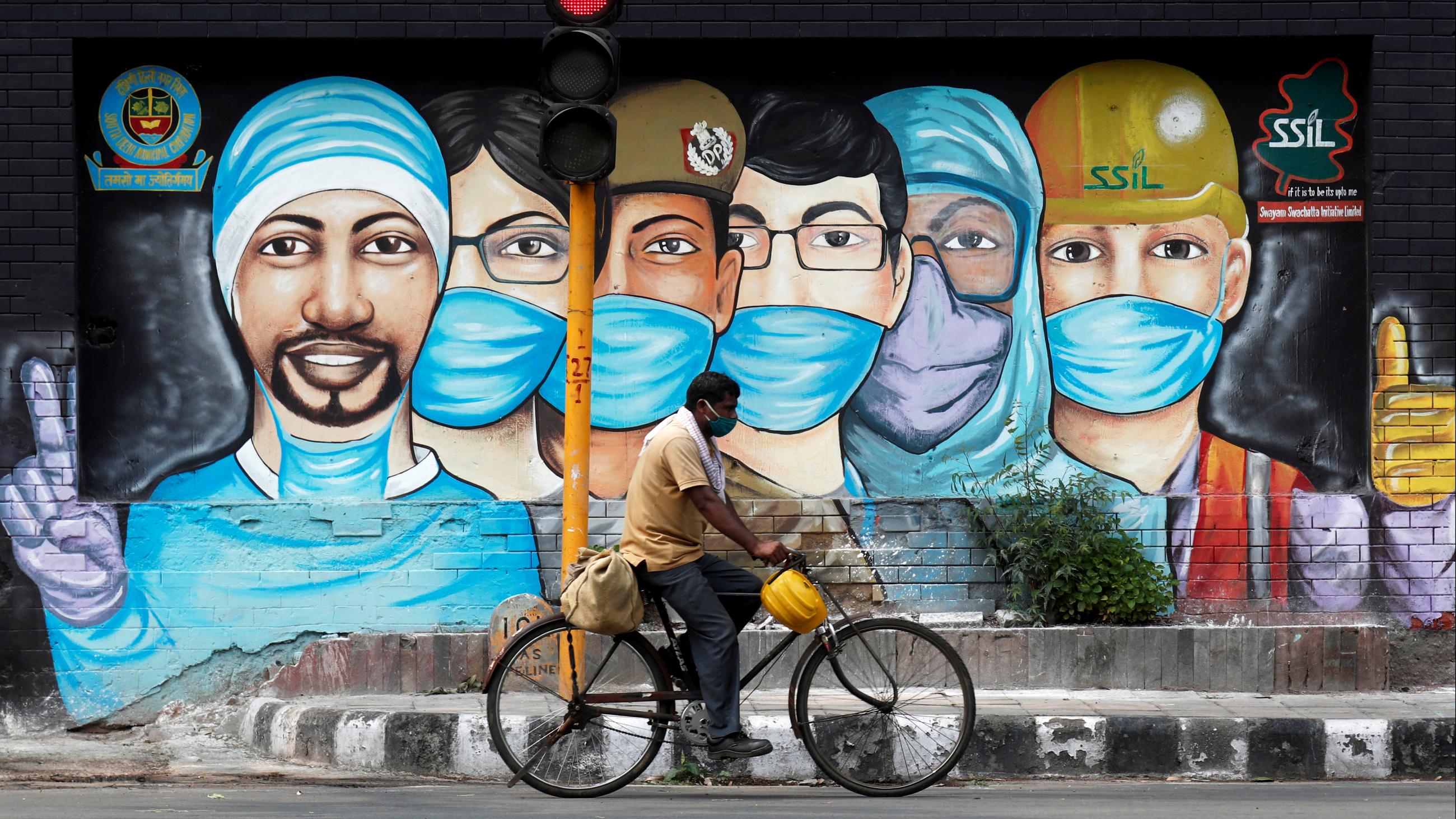 A man rides his bicycle past street art during the coronavirus disease outbreak in New Delhi, India, on July 17, 2020.
