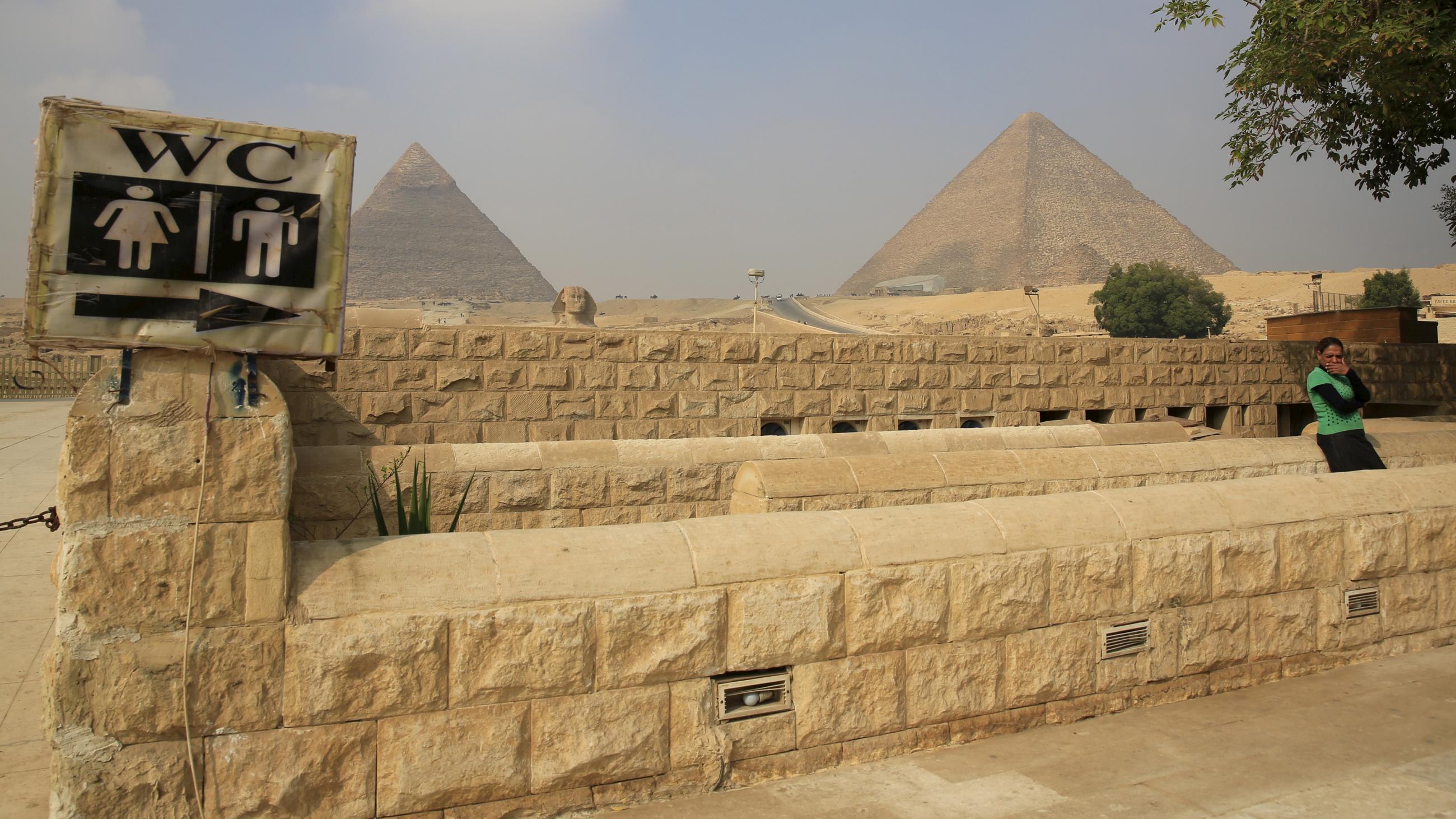 A woman waits in front of a toilet in front of the Sphinx at the Giza Pyramids on the outskirts of Cairo, Egypt, on November 8, 2015.