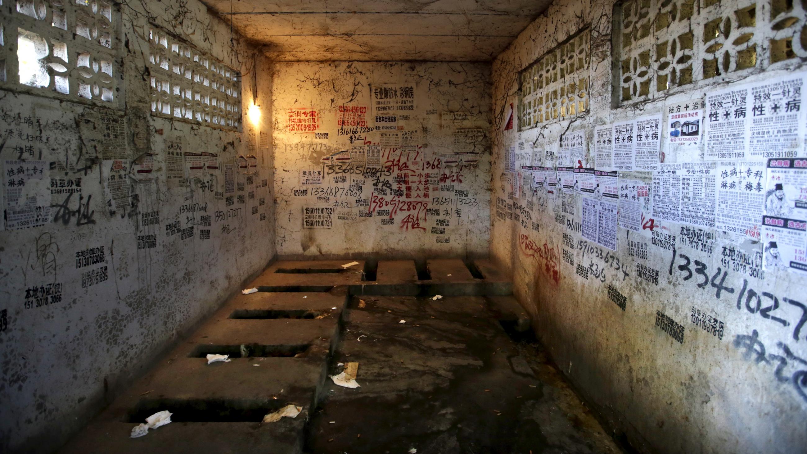 Posters, including those advertising treatments for sexually transmitted diseases, are stuck to the walls of a public toilet in a residential area for migrant workers in Shigezhuang village, Beijing, China, October 13, 2015.