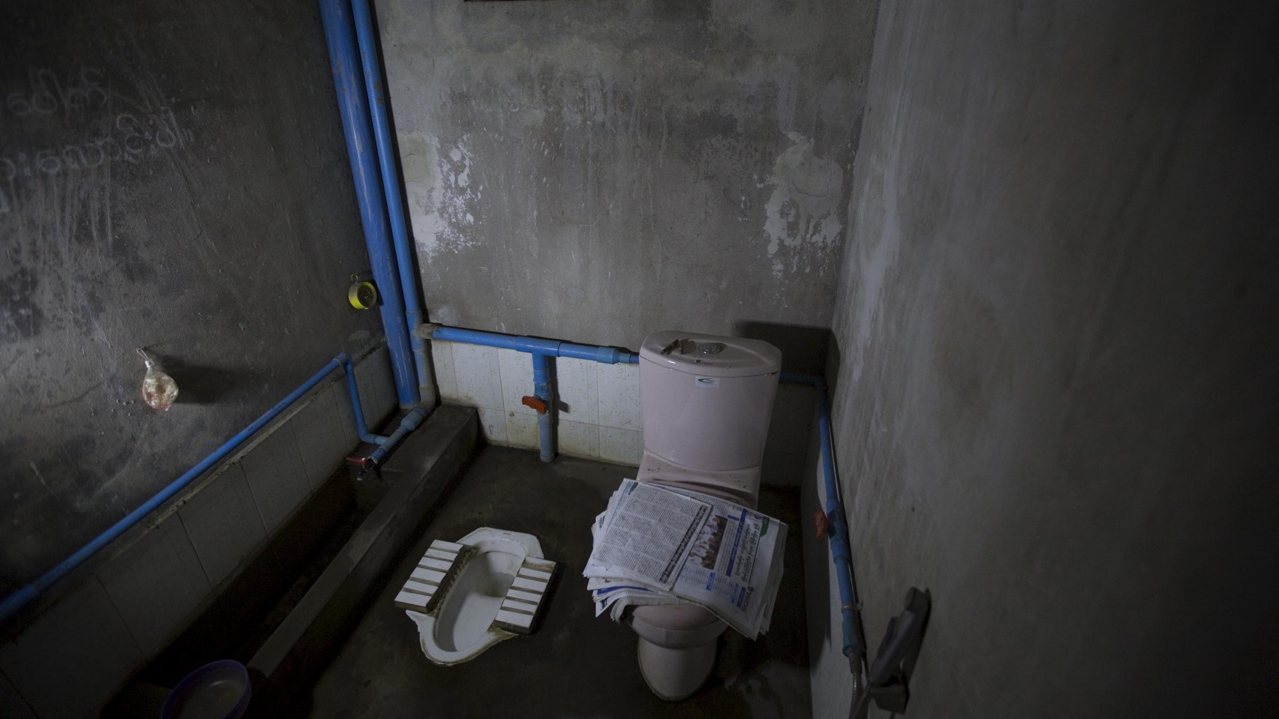 Newspapers are seen on a toilet seat next to a traditional squat toilet in a private home in Mandalay, Myanmar, October 5, 2015.
