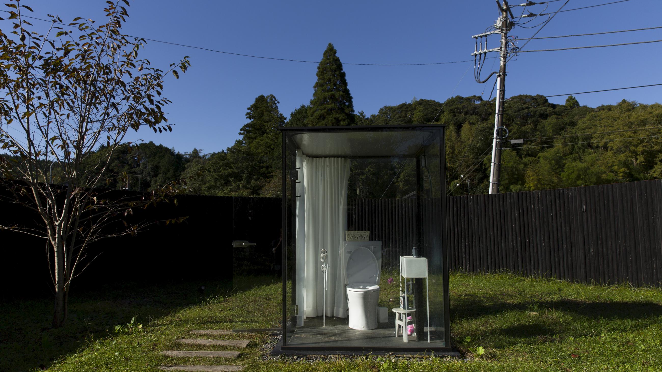 women's restroom is a glass cubicle with a fully functioning toilet that stands in a garden,