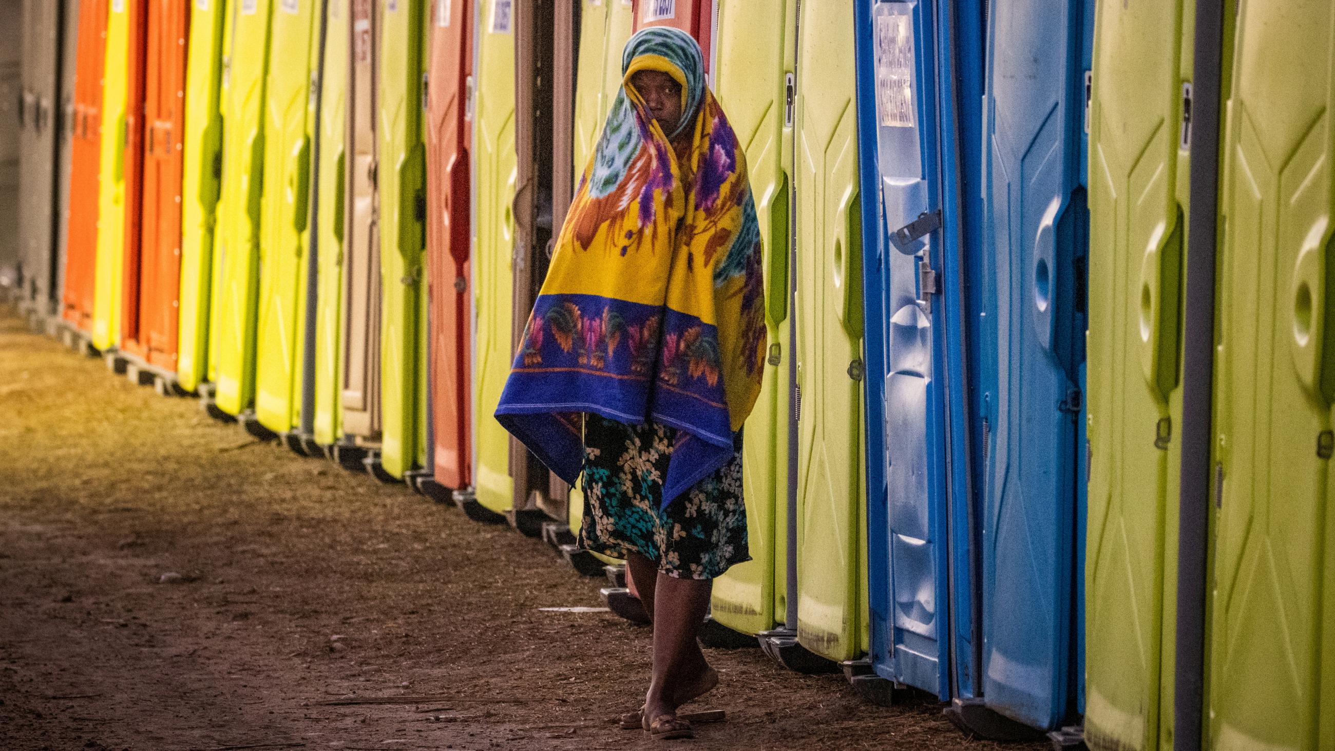 A migrant woman walks past a row of portable toilets at a makeshift border camp along the International Bridge in Del Rio, Texas