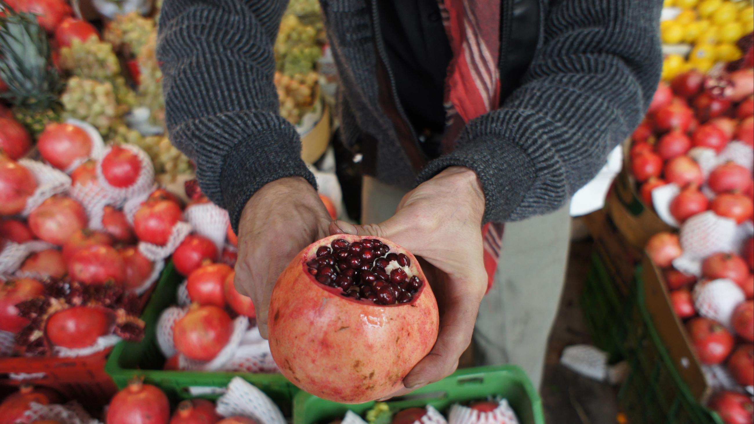 An Iranian shopkeeper at a bazaar cuts a pomegranate to display to customers who are shopping for Yalda Night in northern Tehran December 21, 2010