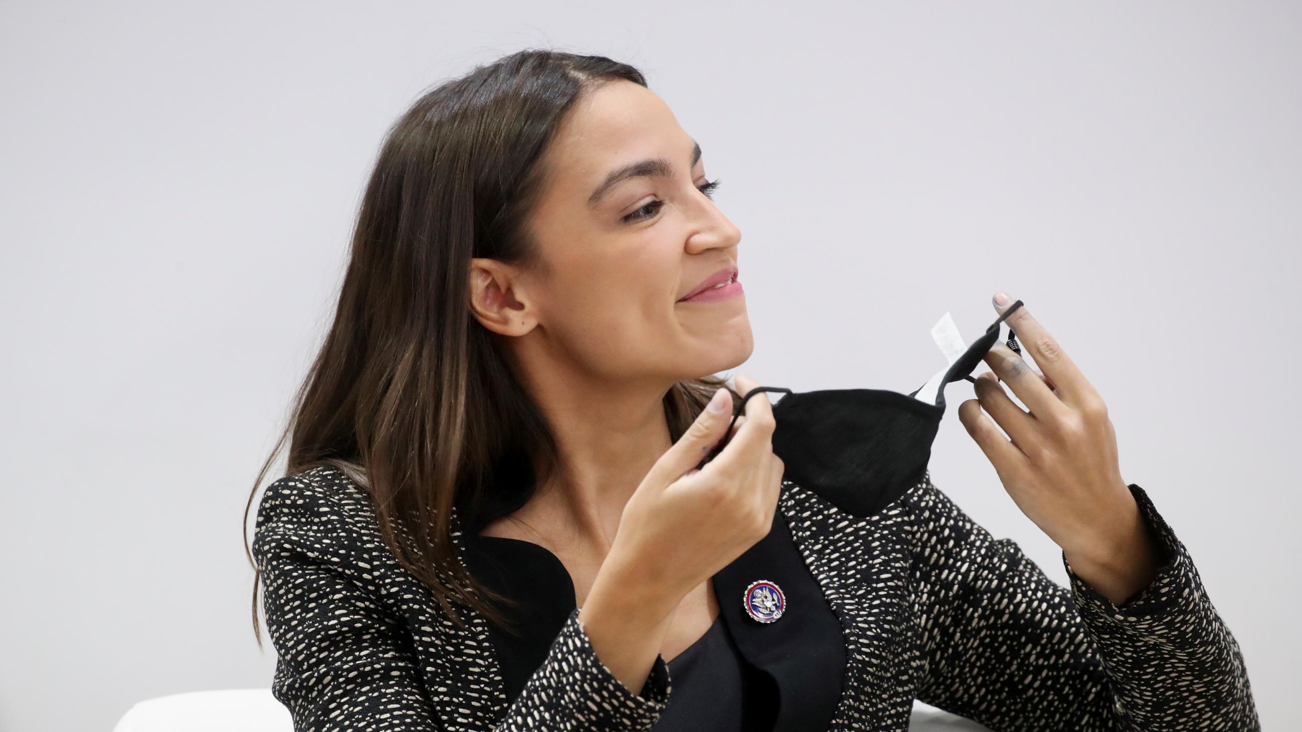 U.S. Representative Alexandria Ocasio-Cortez holds her face mask as she addresses a panel at COP26 on November 9, 2021.