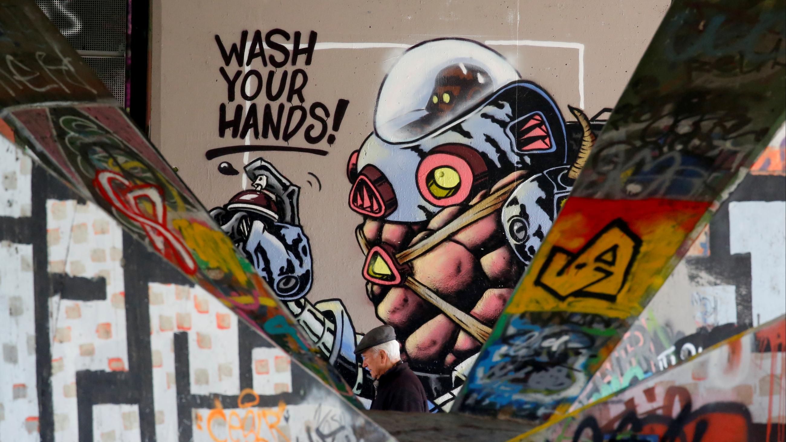 A man passes street art under a bridge during the COVID pandemic in Vienna, Austria, on April 2, 2020.