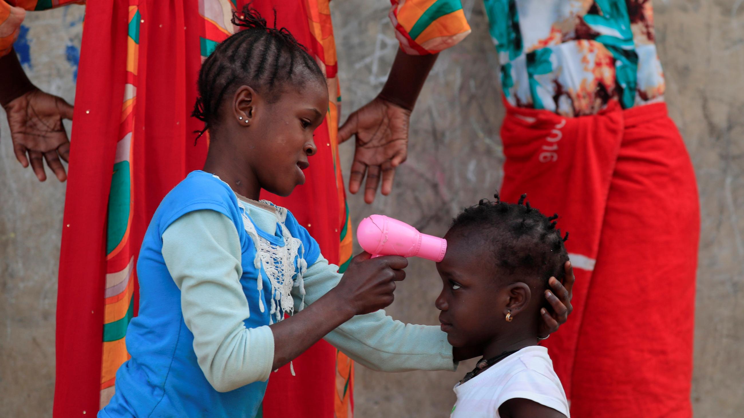 A girl uses a toy hairdryer as an infra-red thermometer on her friend as they play at Hann Bay on the eastern edge of Dakar, Senegal, April 12, 2021