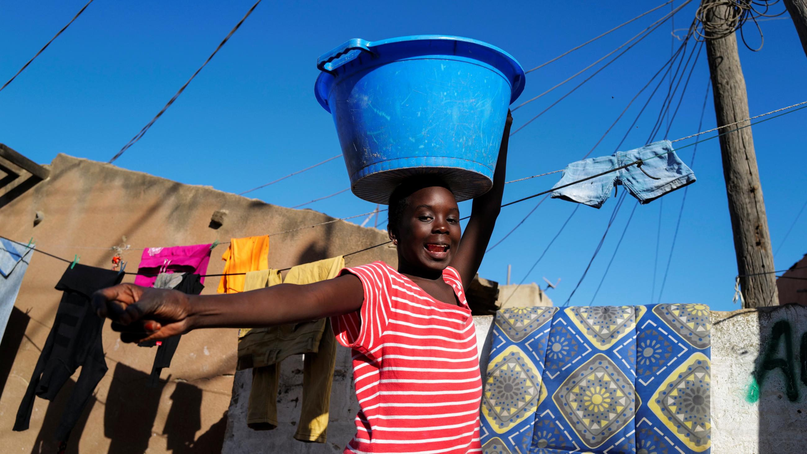 A girl carries a bucket with laundry on her head while heading home as the spread of the coronavirus disease continues, in Yoff neighbourhood, Dakar, Senegal on January 26, 2021