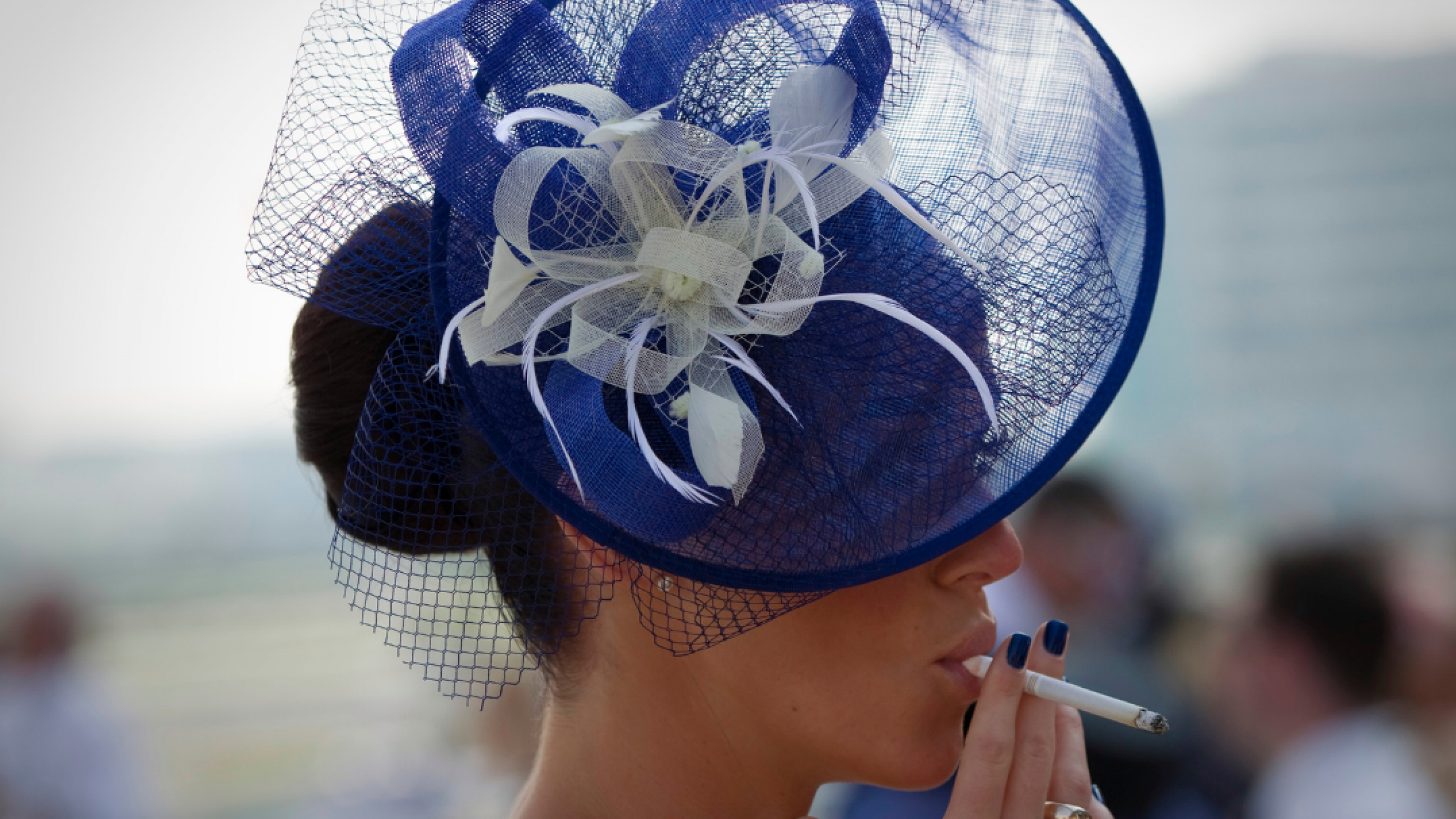 A spectator smokes a cigarette as she waits for the start of the Dubai World Cup horse race at Meydan Racecourse in Dubai, United Arab Emirates on March 29, 2014