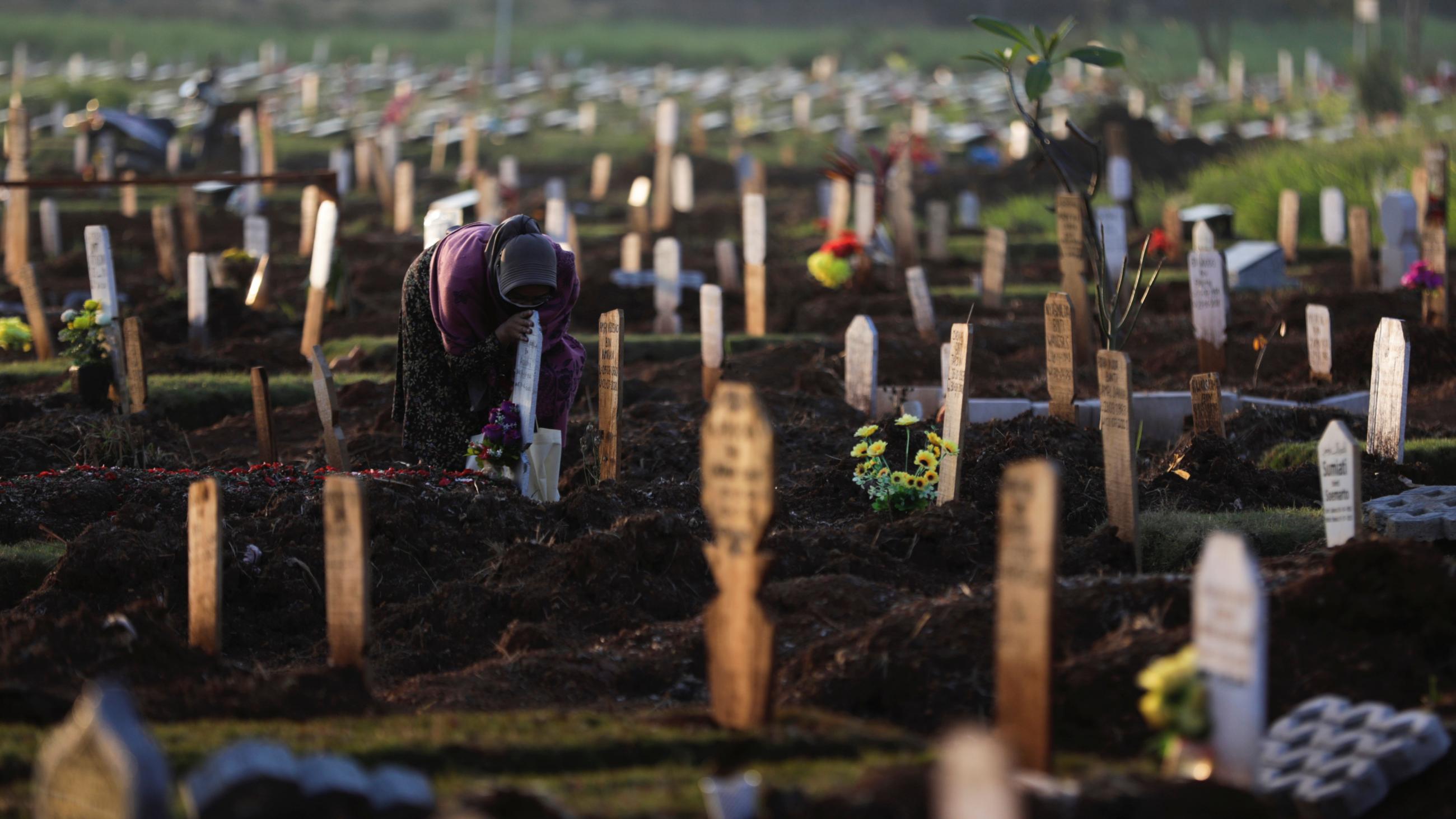 A woman mourns at the grave of her husband who passed away due to COVID-19, at a burial area provided by the government for COVID-19 victims as the country reports a record daily number of COVID-19 de