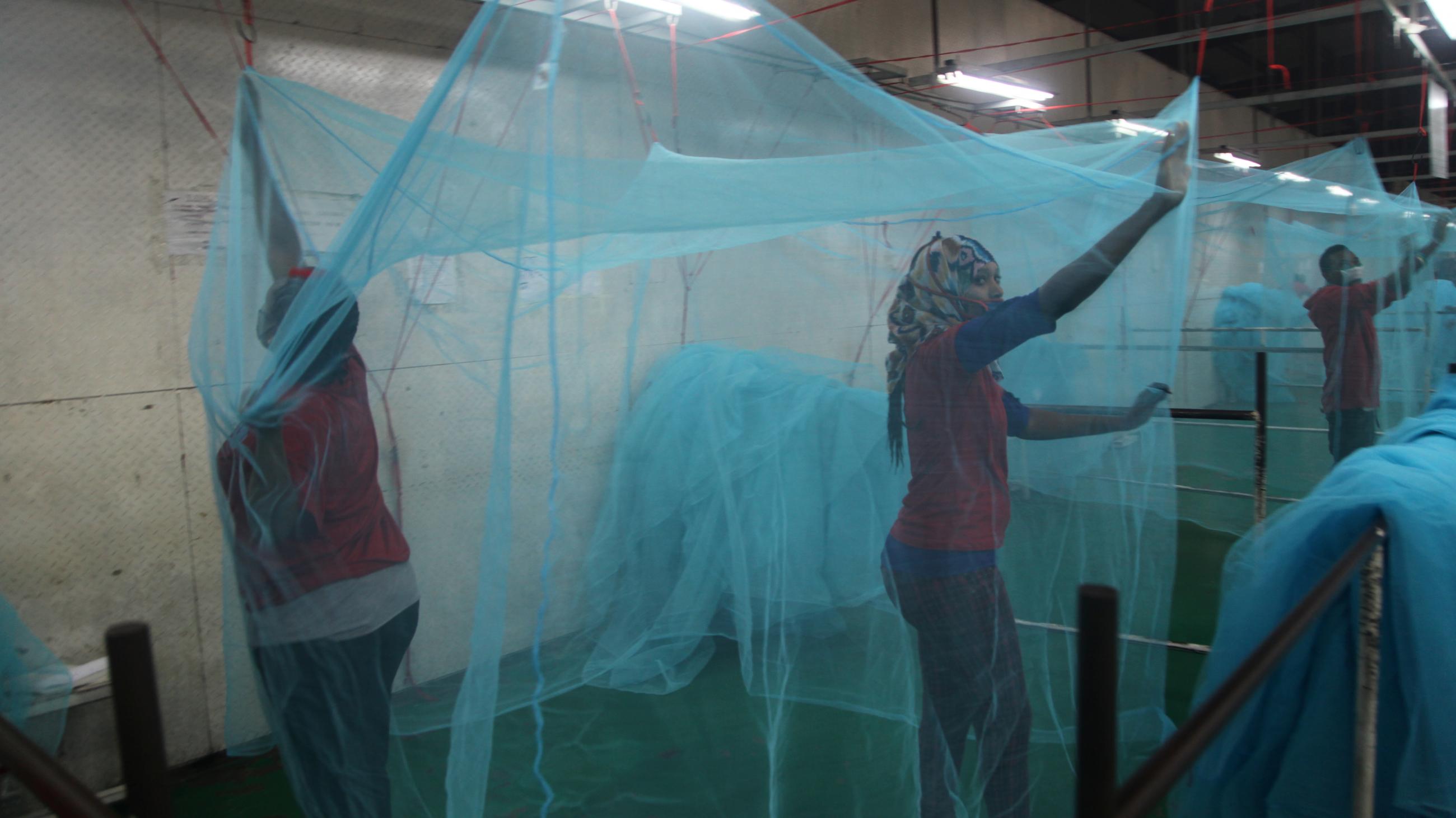 Employees at a bed net factory in Tanzania inspect nets for holes