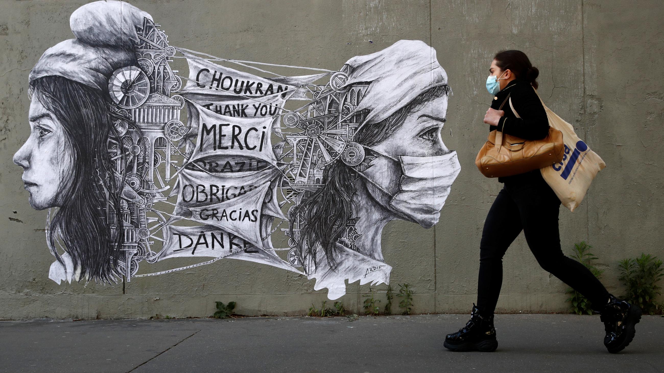 A woman walks past street art thanking frontline workers in Paris, France.