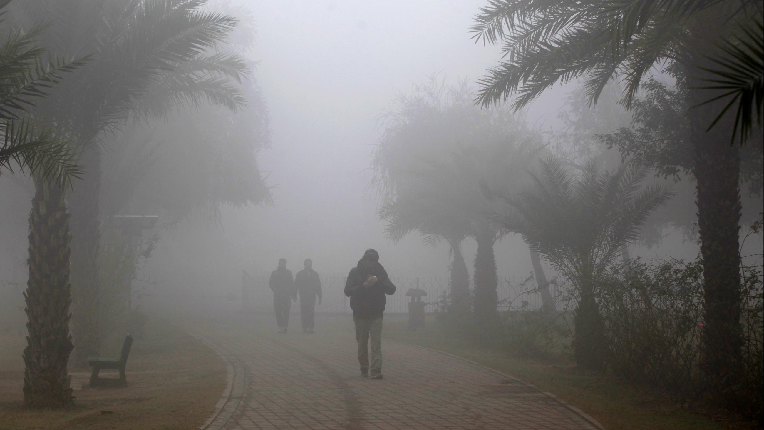 People walk in a park amid dense fog and smog in Lahore, Pakistan, on December 21, 2019