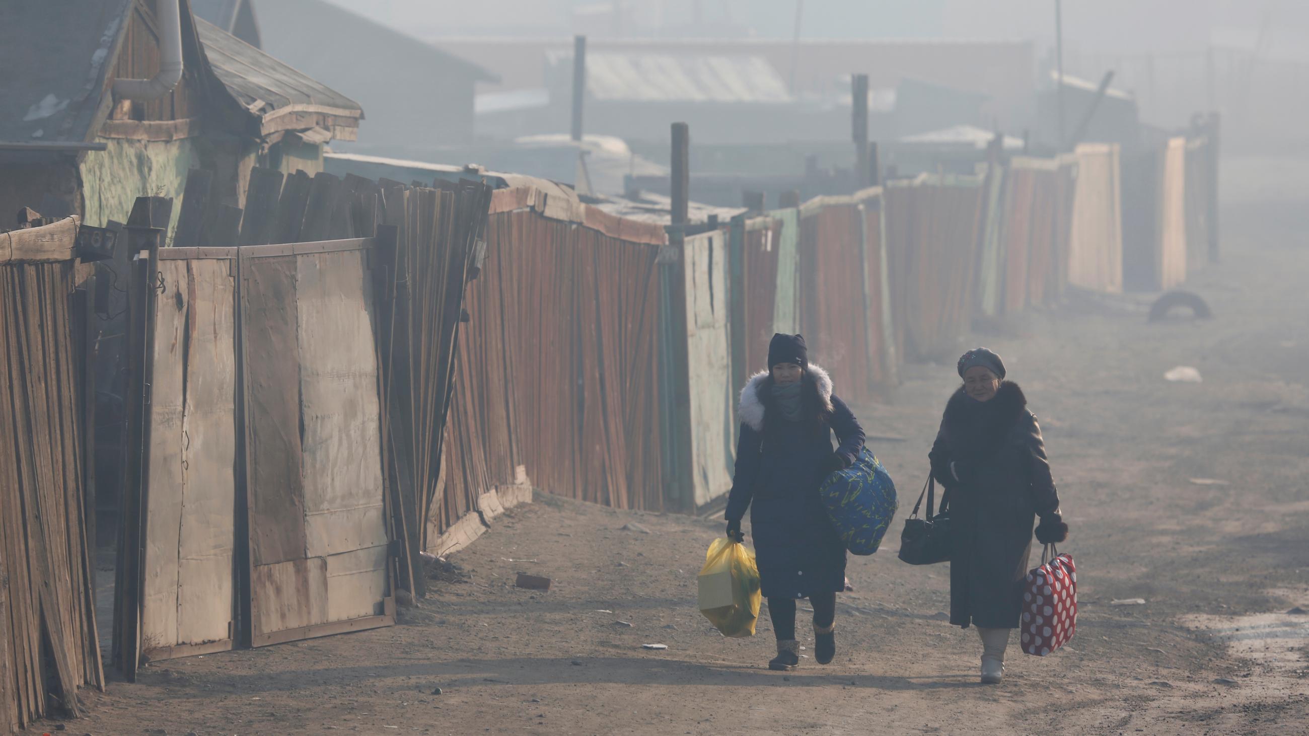 Women walk with their belongings amid smog in Sukhbaatar district of Ulaanbaatar, Mongolia, on January 31, 2019.
