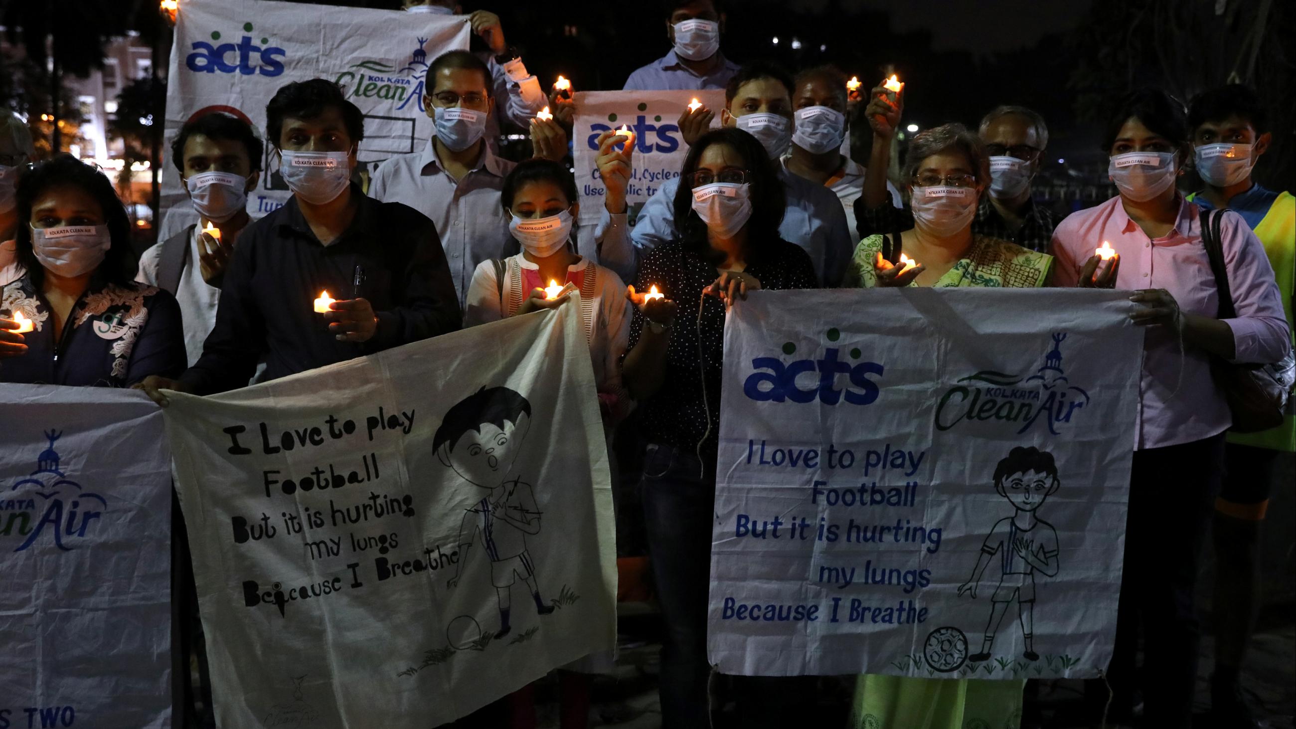 People wearing protective masks hold electric candles as they take part in a campaign to raise awareness about air pollution in Kolkata, India, on November 12, 2019.