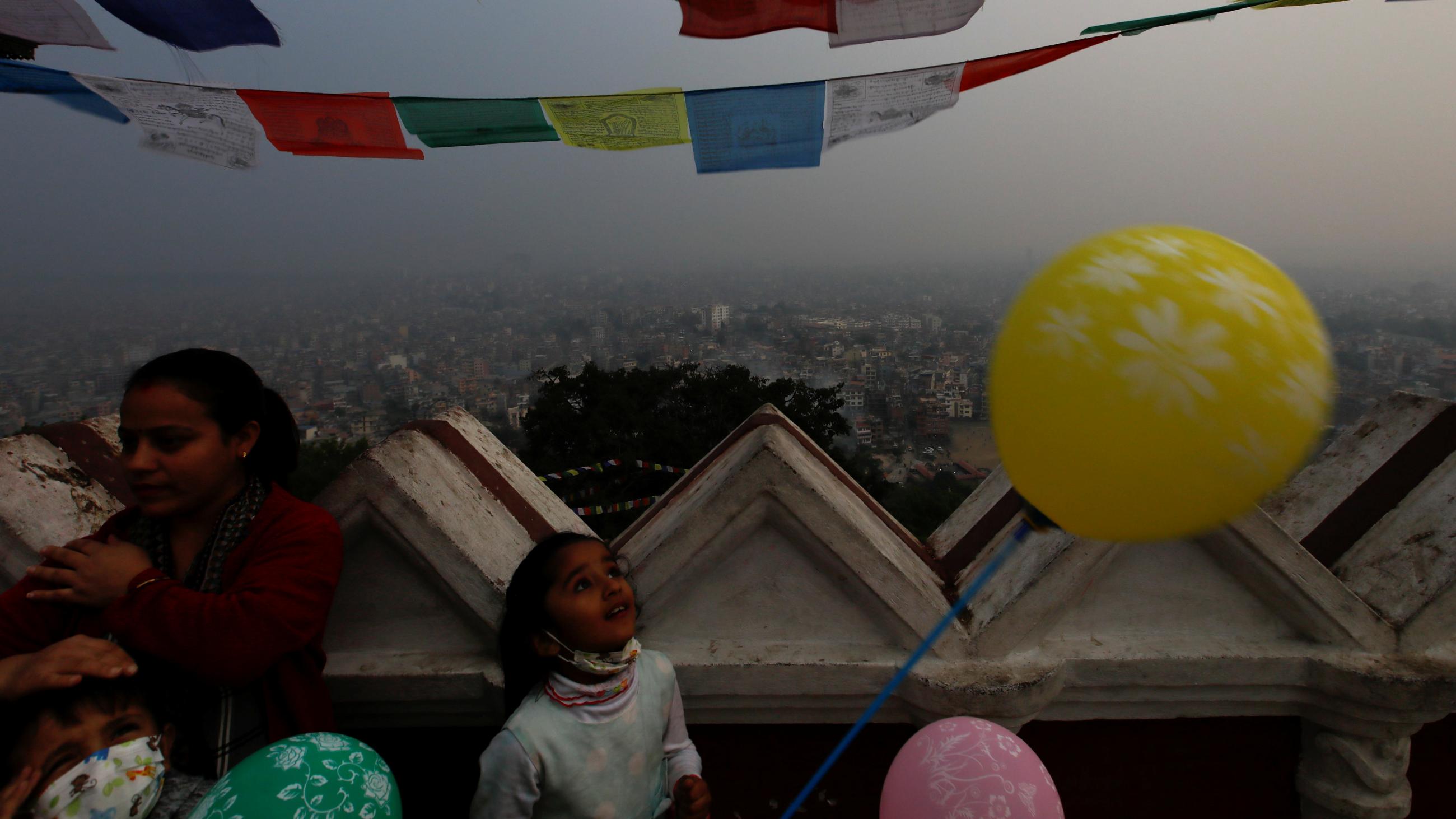 A girl holding a balloon looks towards the sky during a smoggy day as the government has ordered schools to close for four days after the air pollution climbed to hazardous levels, forcing millions of students to stay home across the country,