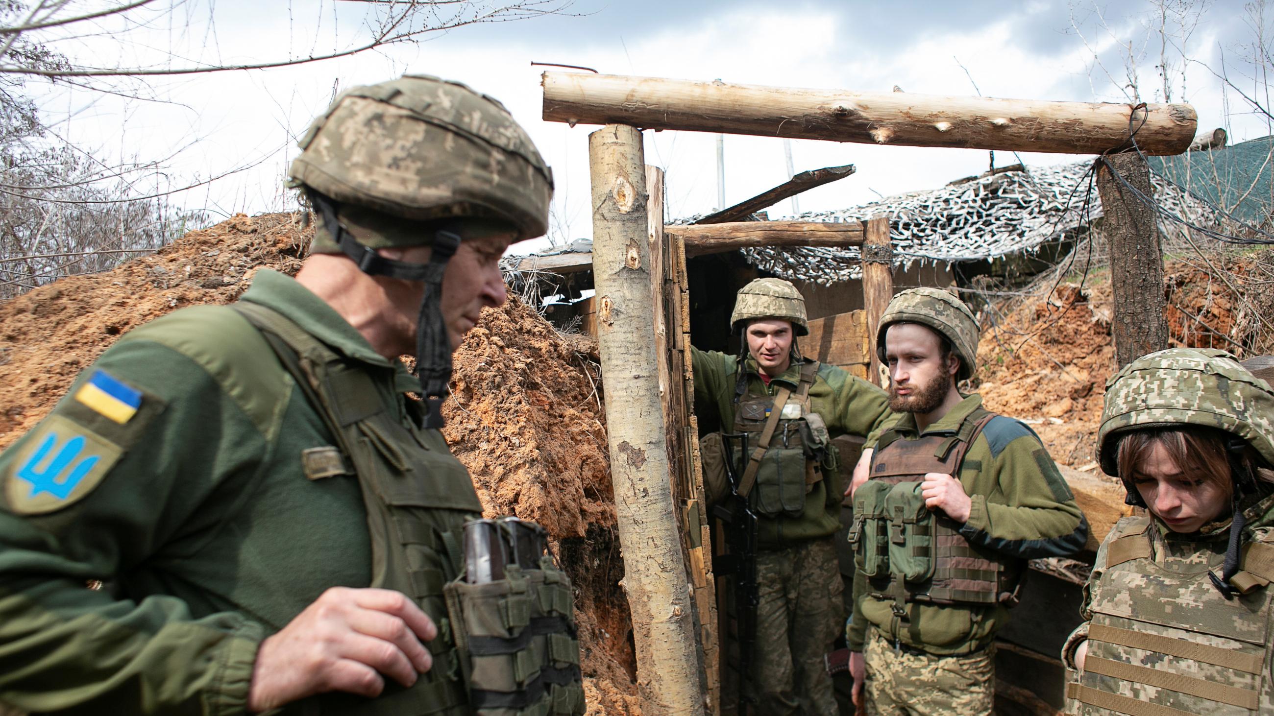 One female and three male Ukrainian soldiers stand in a trench on the front lines of the war in Donbas.