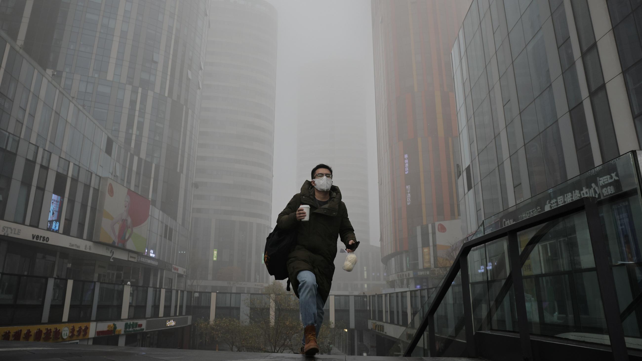A man walks in the Sanlitun shopping district on a polluted day, in Beijing, China,