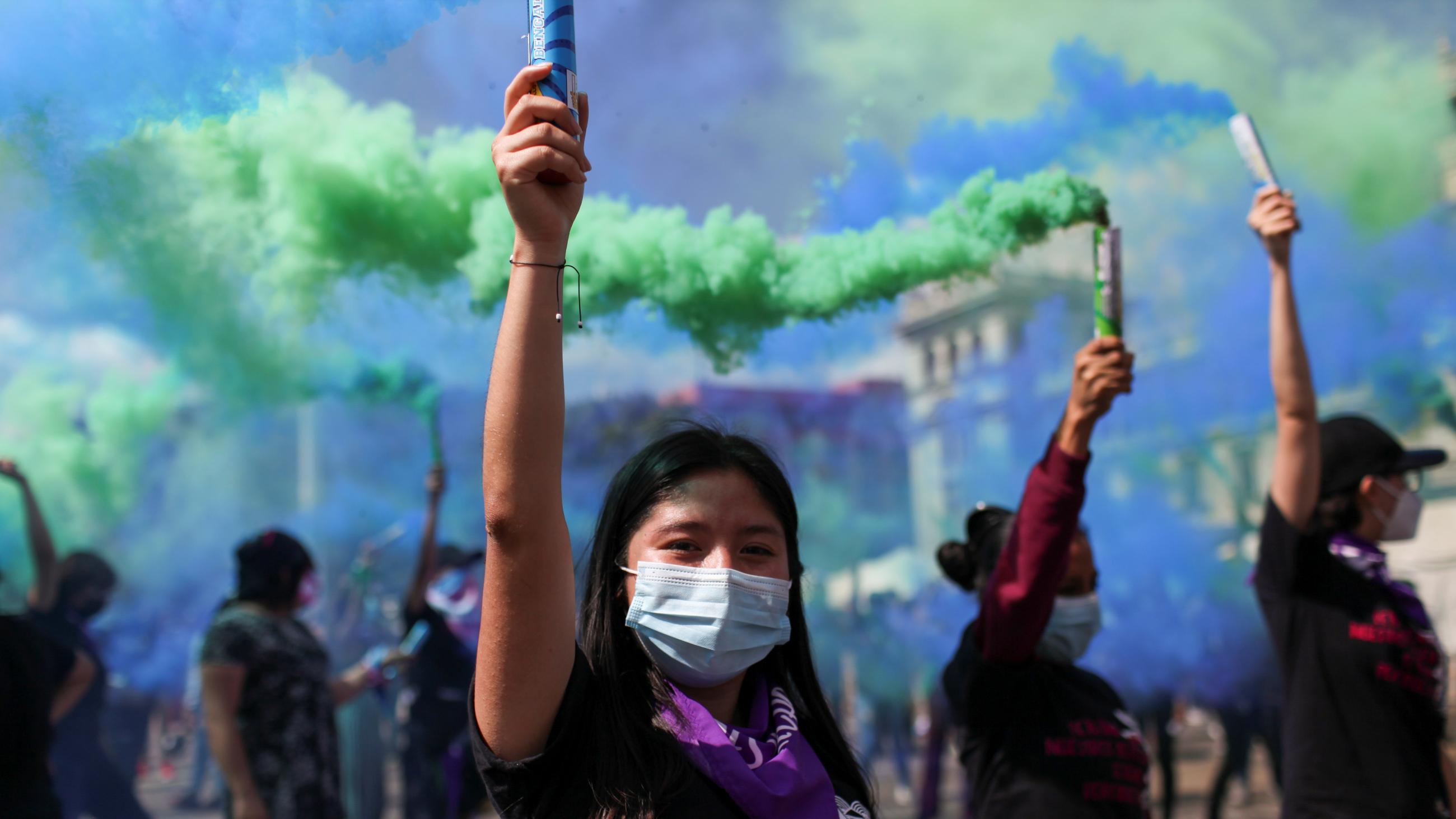 Women hold up smoke bombs during a protest to mark the International Day for the Elimination of Violence Against Women, in Guatemala City, Guatemala November 25, 2021