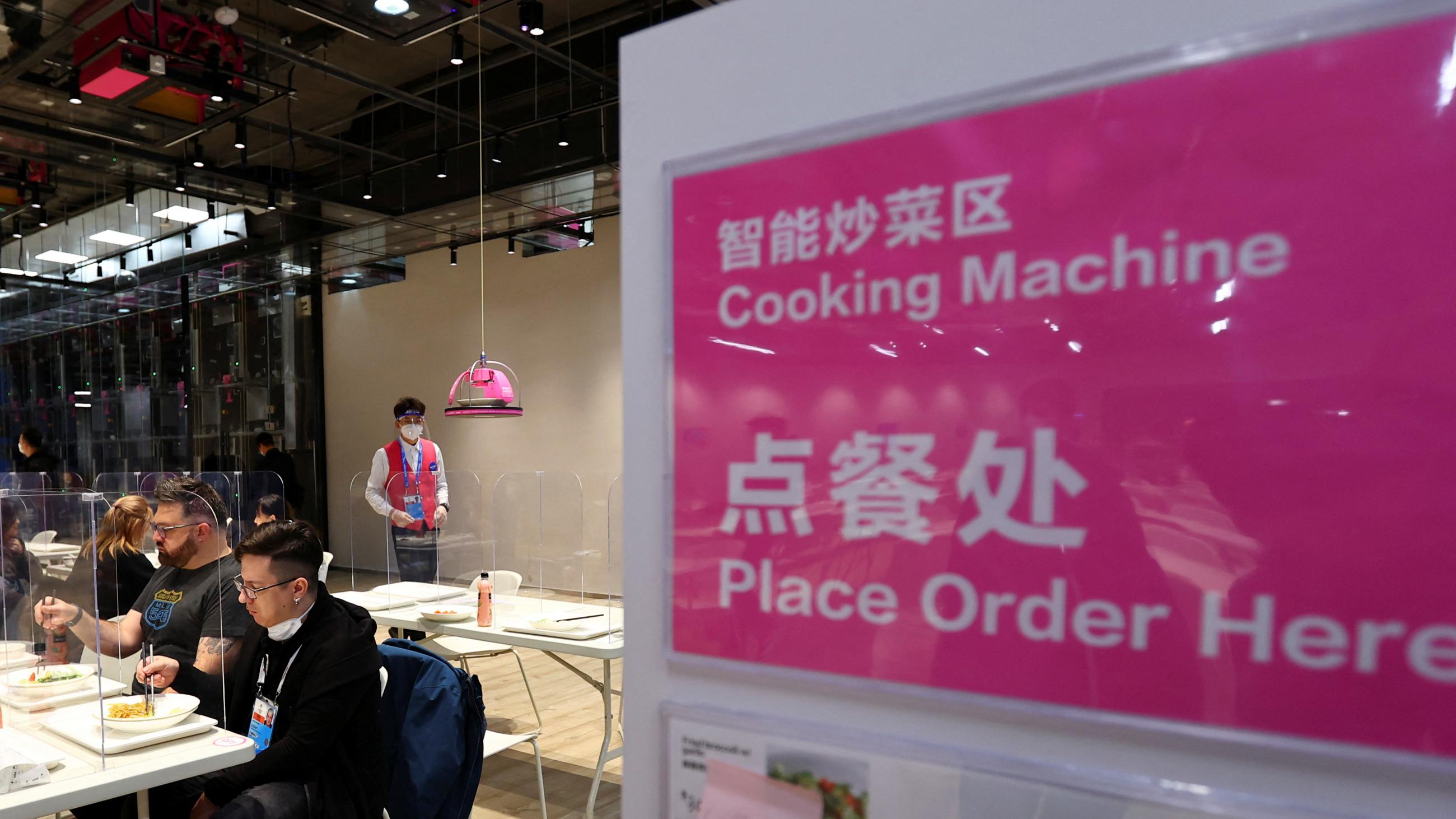 Facility staff observes a lunch delivered by a robotic cooking machine which cooked the meal at the dining hall at the Main Press Centre ahead of the Beijing 2022 Winter Olympics
