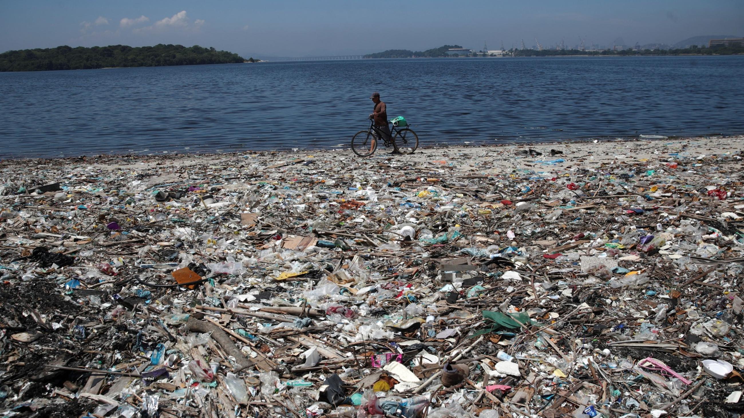 A man walks by plastic waste at a polluted beach on the banks of Guanabara Bay, in Rio de Janeiro, Brazil, on March 16, 2022.