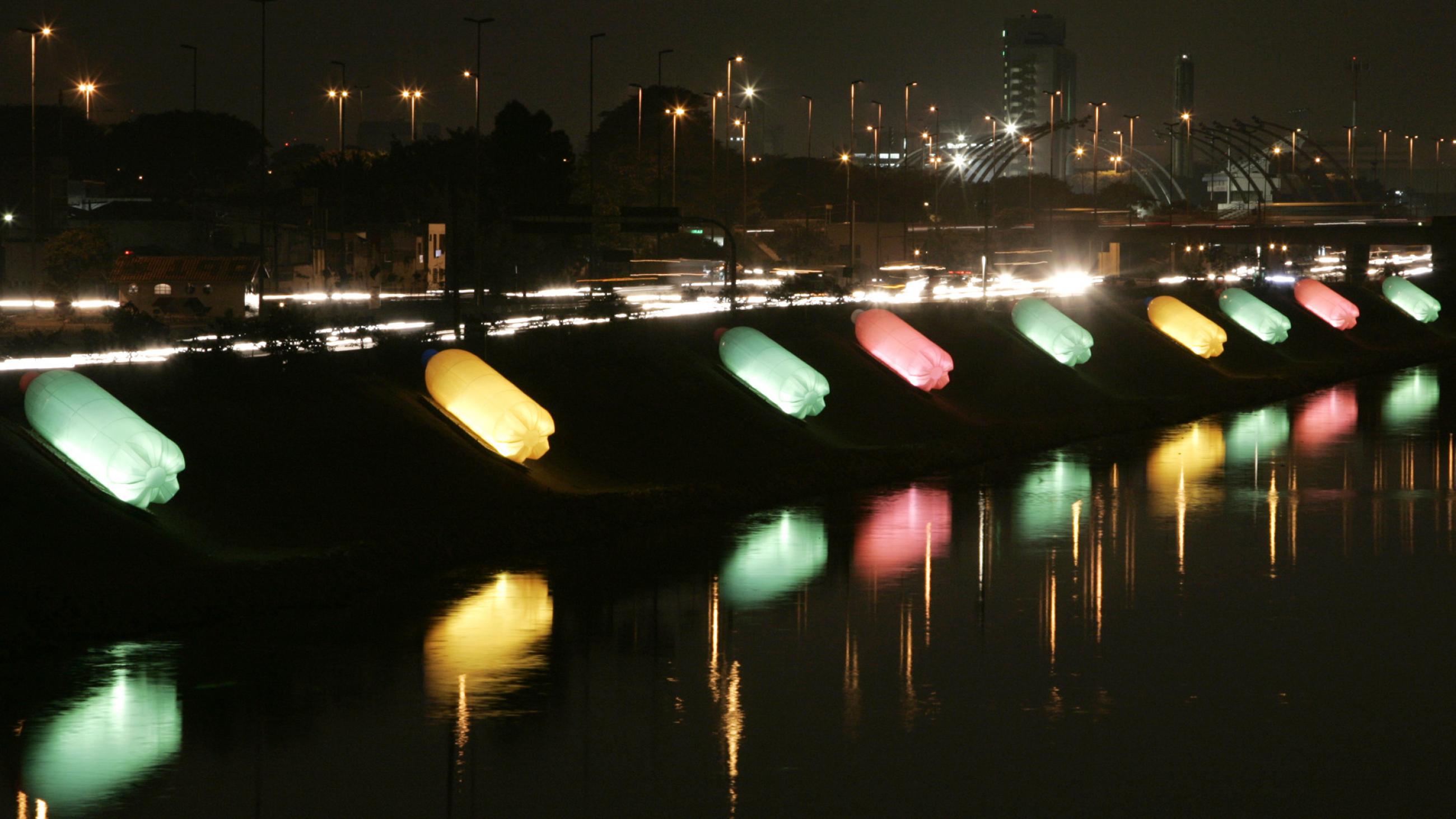plastic bottles, illuminated by colorful lights, are photographed along the tiete river in brazil at night