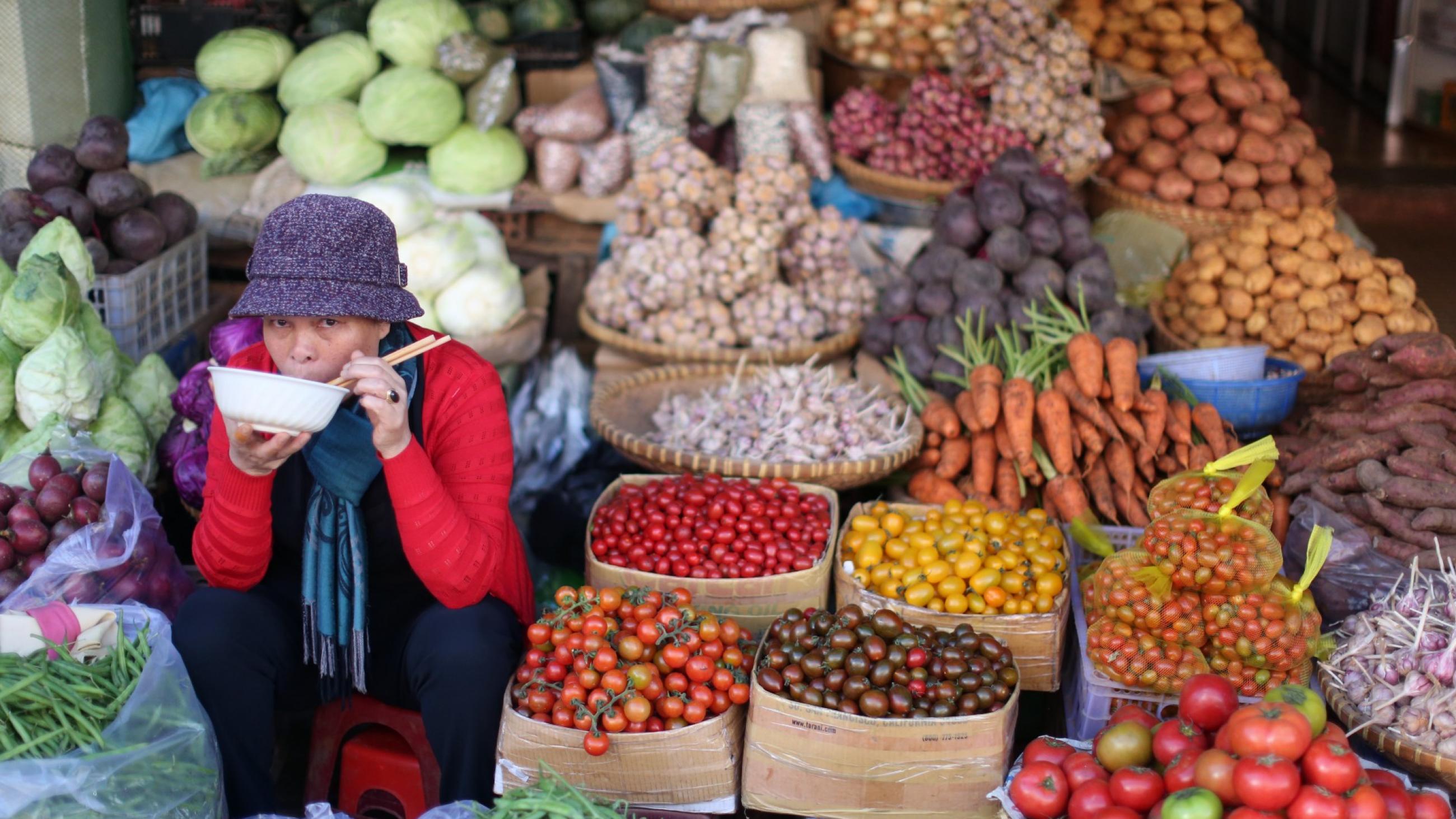 female fruit vendor sits at her kiosk in a market, in Dalat, Vietnam.
