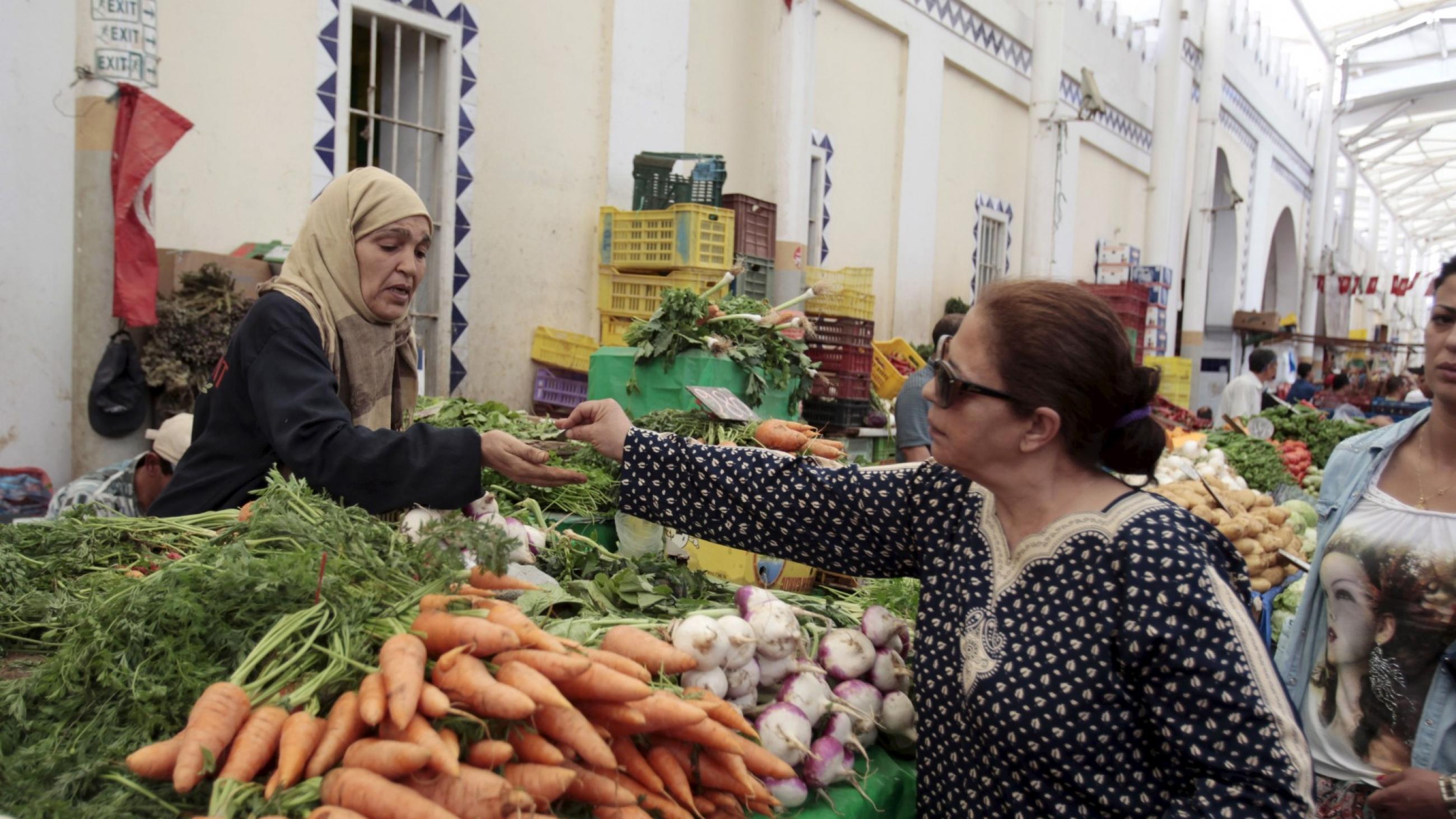 A woman buys vegetables from a vendor on the first day of Ramadan, the Muslim holy fasting month, in a market downtown in Tunis,Tunisia, on June 18, 2015. 