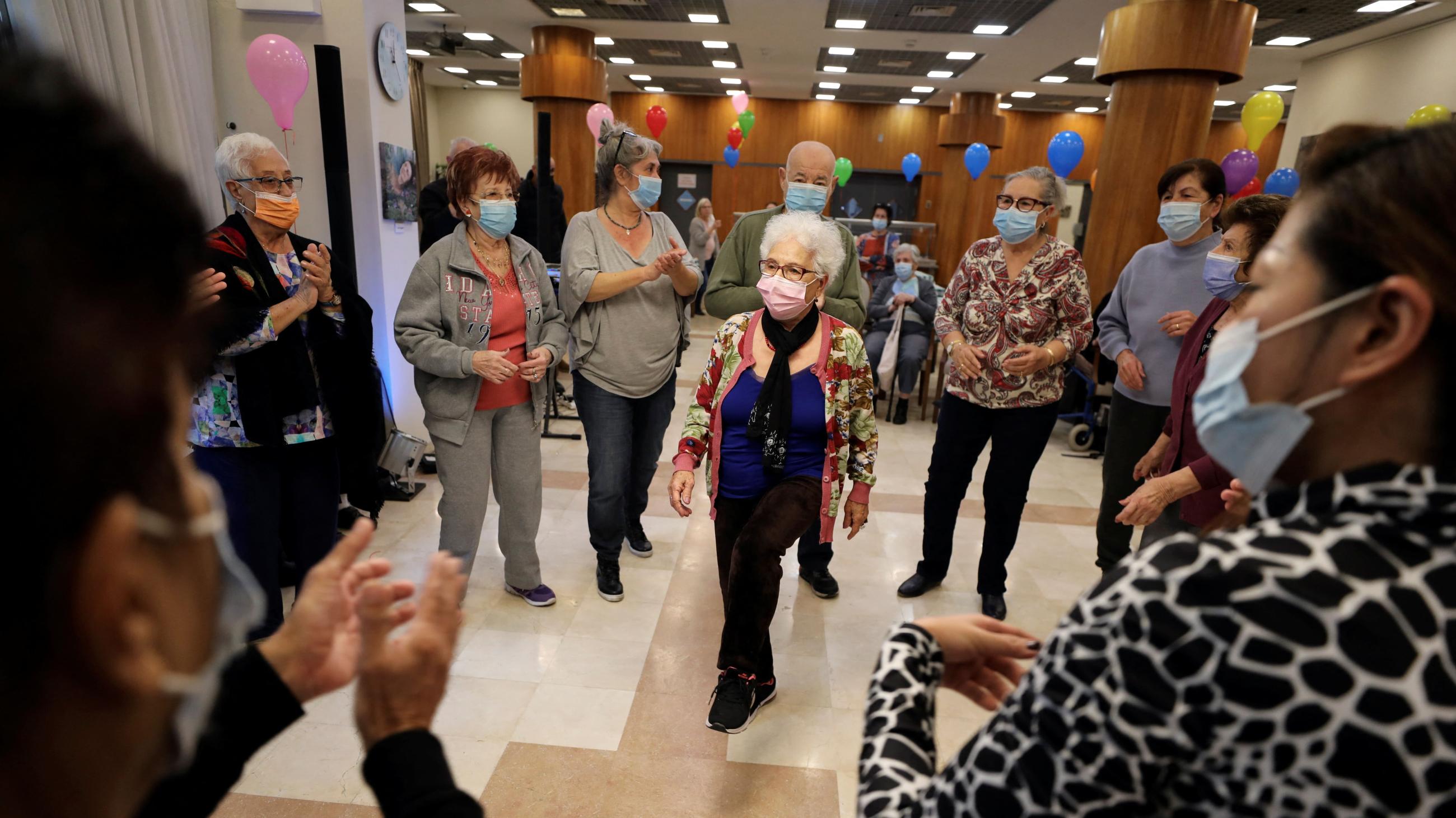 Eighty-three-year-old Rachel Gershom and other senior citizens dance at a vaccination party before they receive a fourth dose of the COVID-19 vaccine after Israel approved a second booster shot for the immunocompromised, people over sixty years, and medical staff, in a retirement home, in Netanya, Israel, on January 5, 2022.