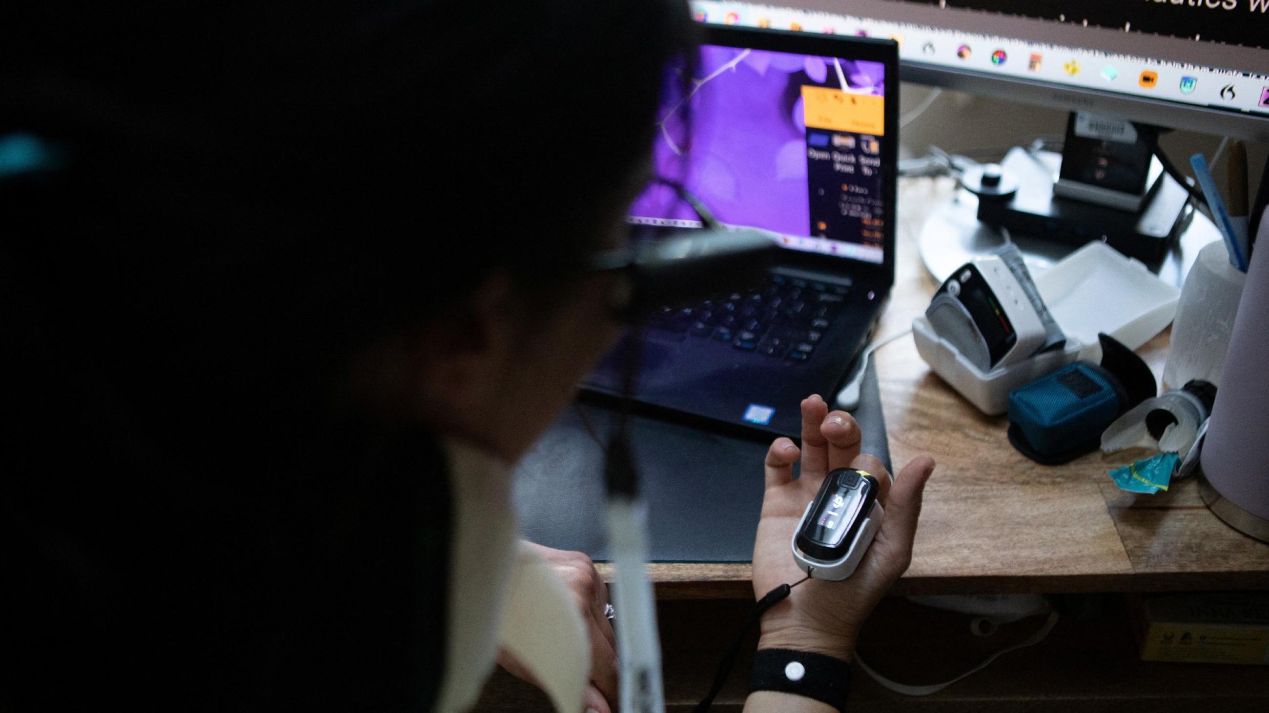 Lauren Nichols, who has long COVID, takes a break from work to read her blood oxygen levels and heart rate from a machine on her finger in her home in Andover, Massachusetts, U.S., August 3, 2022.