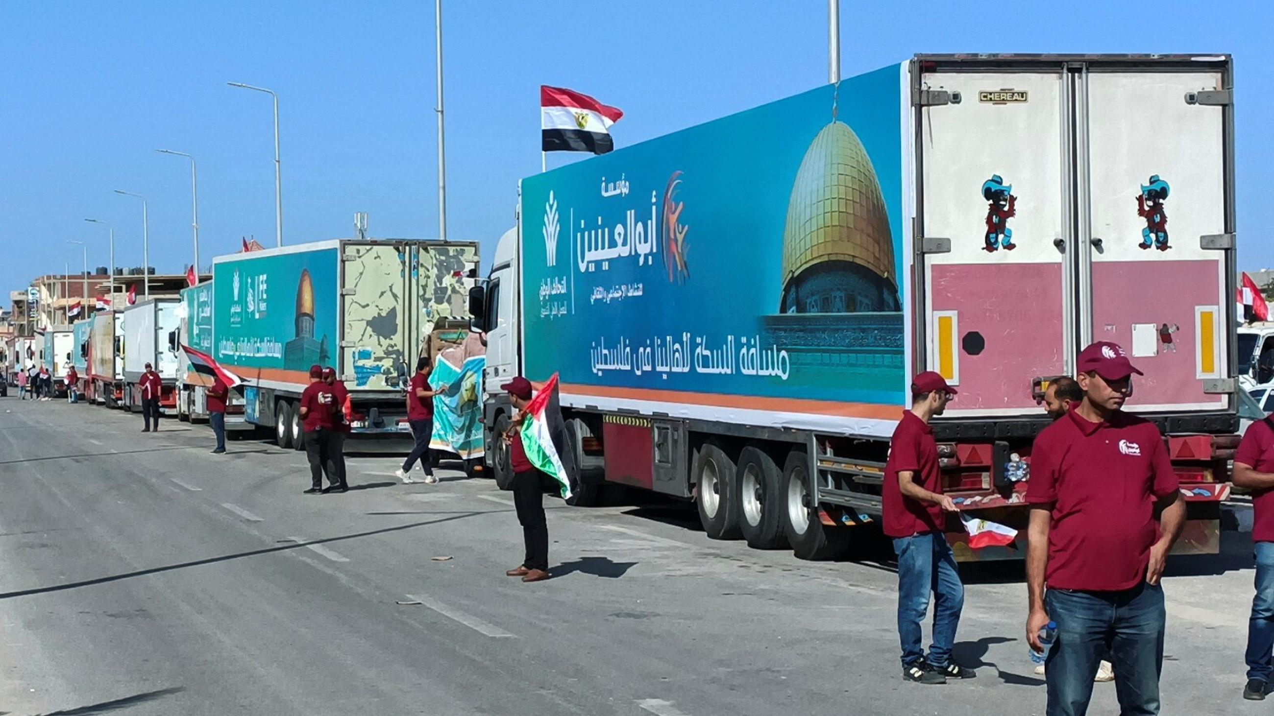 A line of trucks is seen surrounded by people waiting for the agreement. 