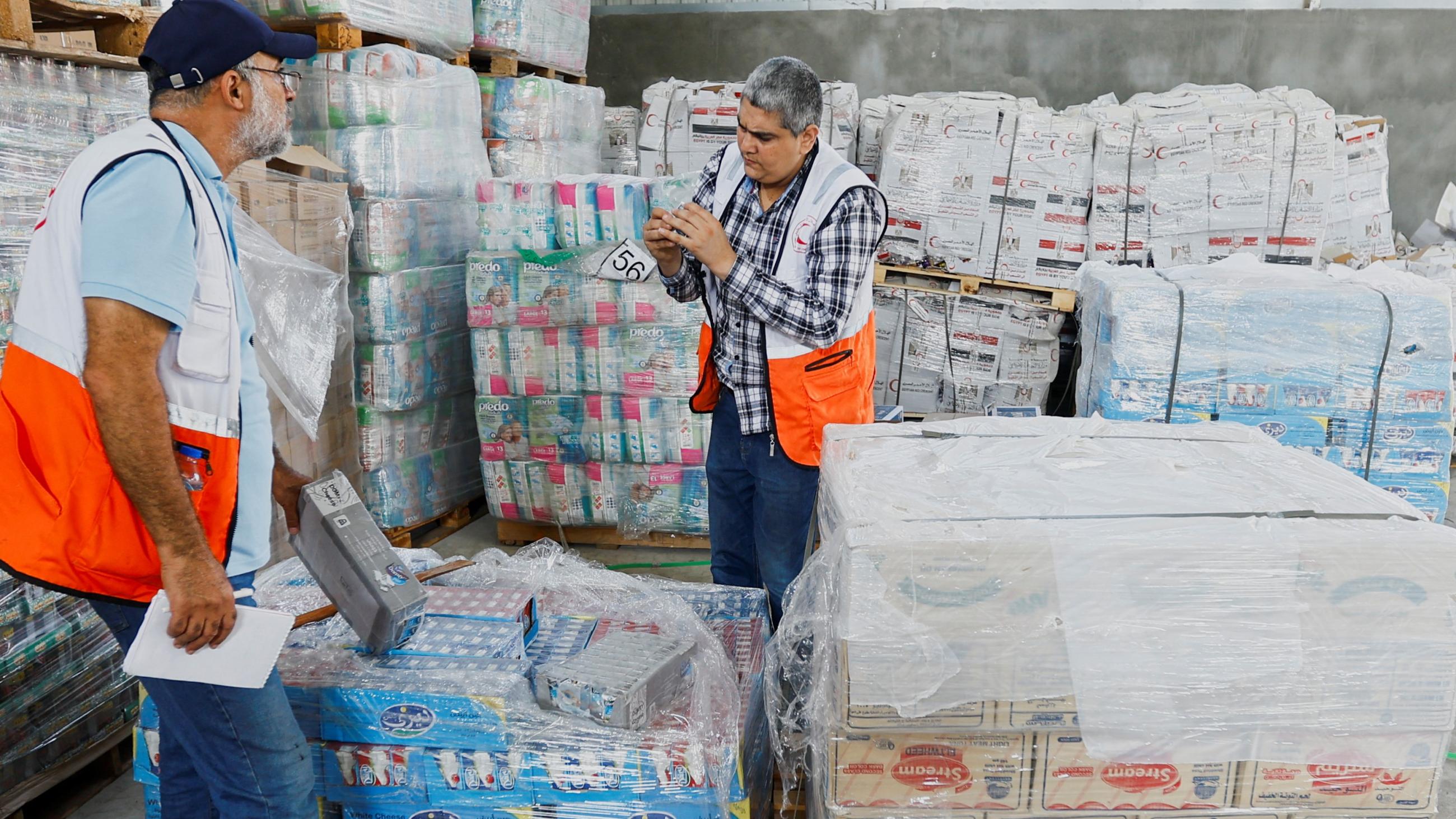 Two men are seen over containers of aid 