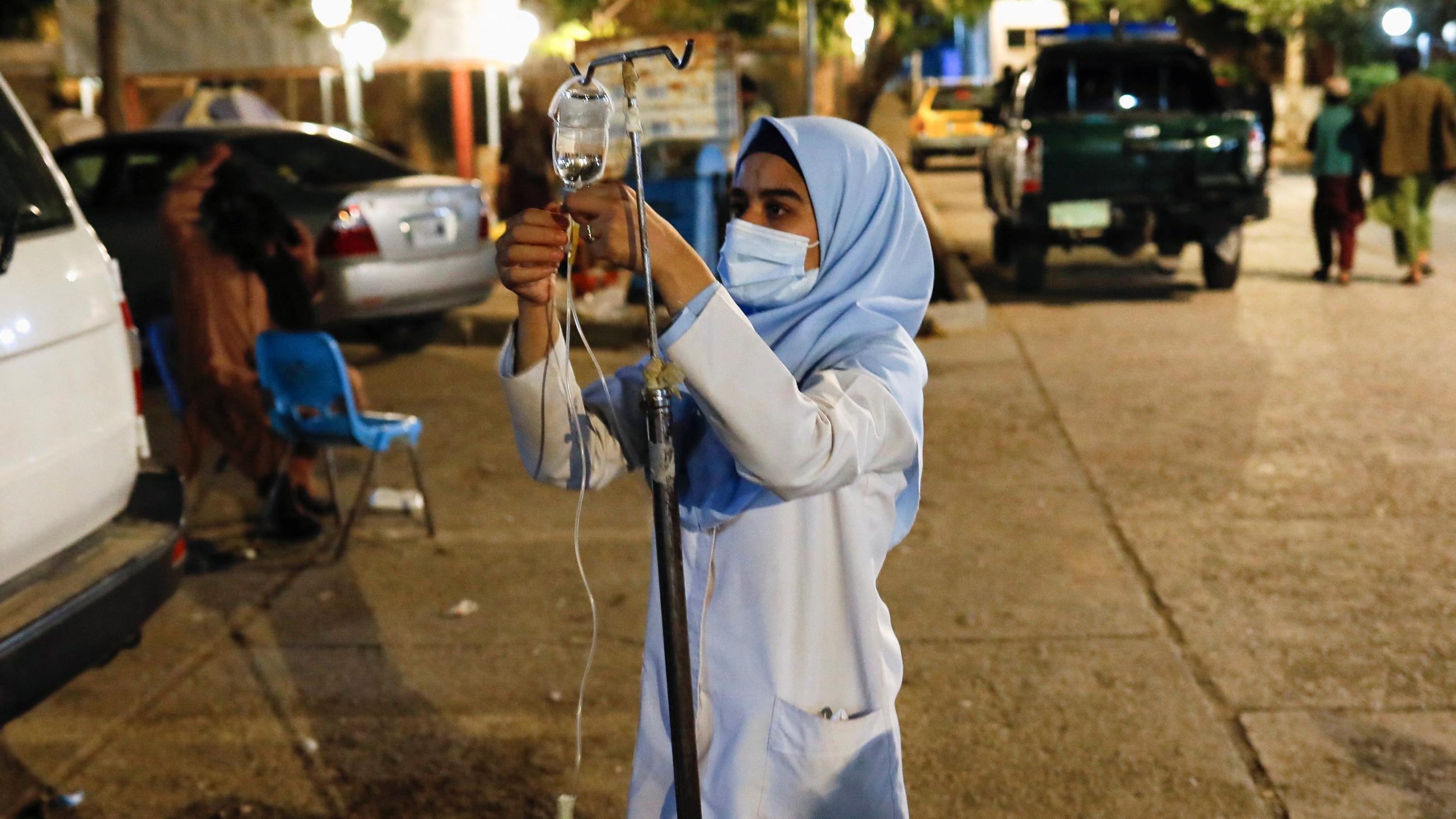 An Afghan nurse prepares serum drops for a victim of an earthquake in a hospital.