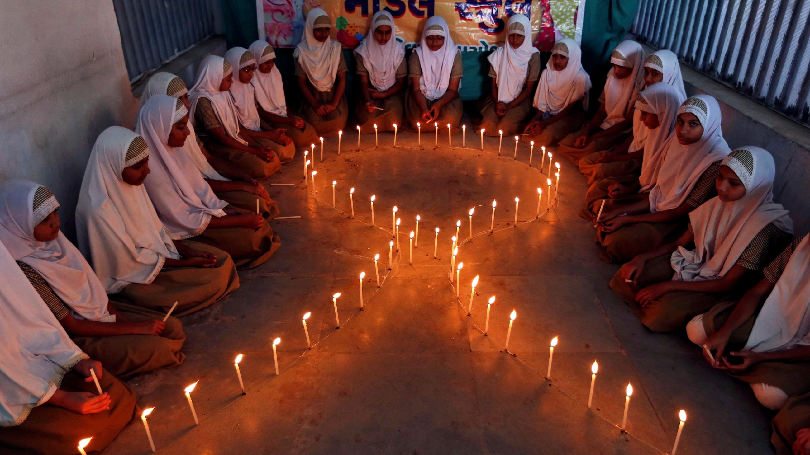 School girls light candles in the shape of a ribbon during a HIV/AIDS awareness campaign ahead of World Aids Day, in Ahmedabad, India November 30, 2016.