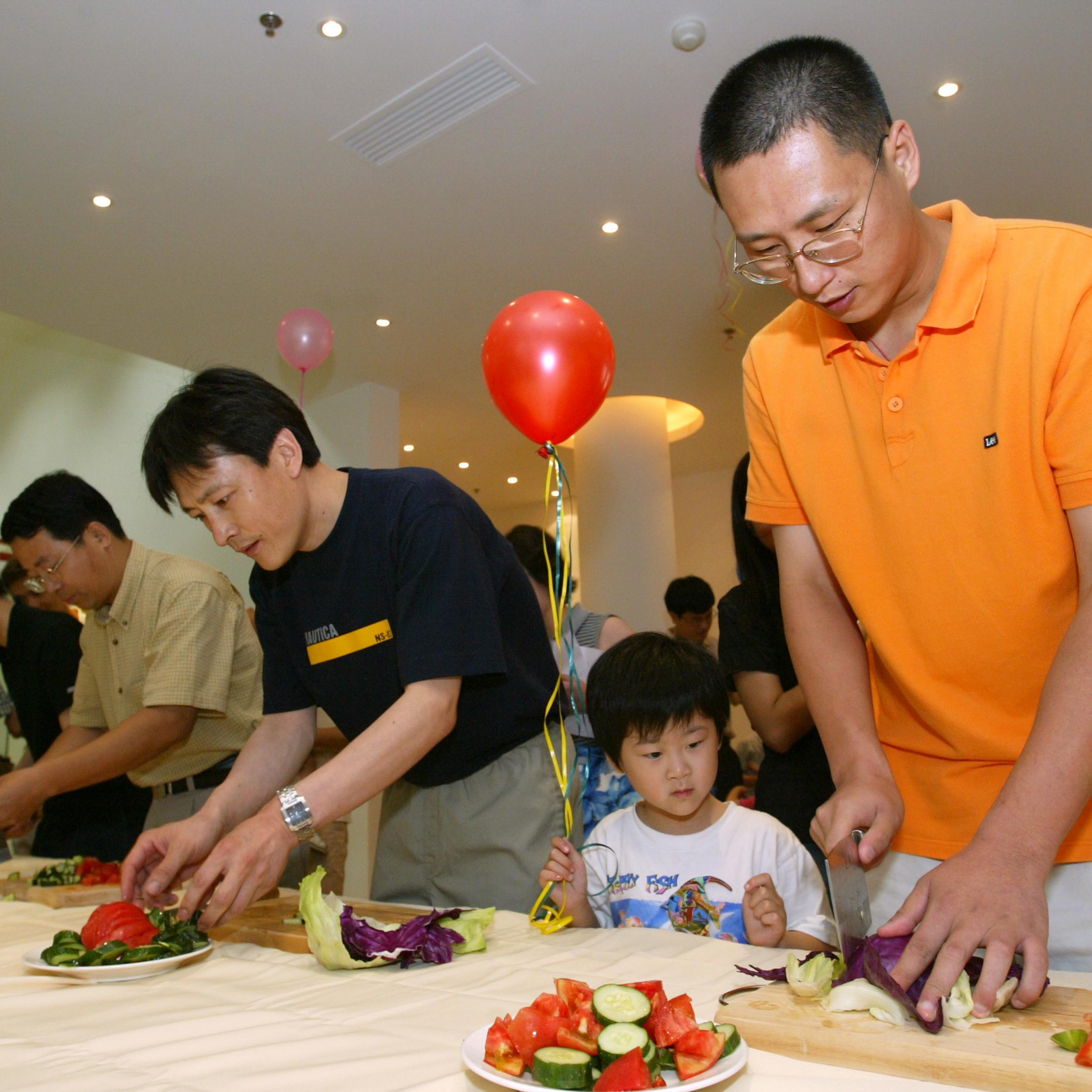 Chinese fathers compete in "Salad Making Contest" at Tsinghua Garden residential estate to celebrate Father's Day in Shanghai, on June 20, 2004. 