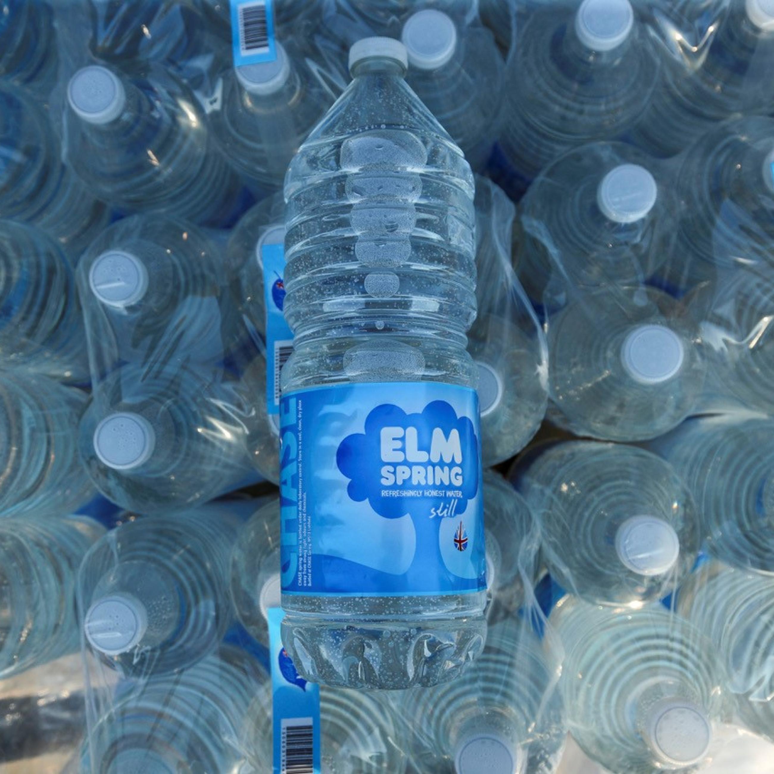 A view from above of dozens of bottles of water with blue labels and white caps.