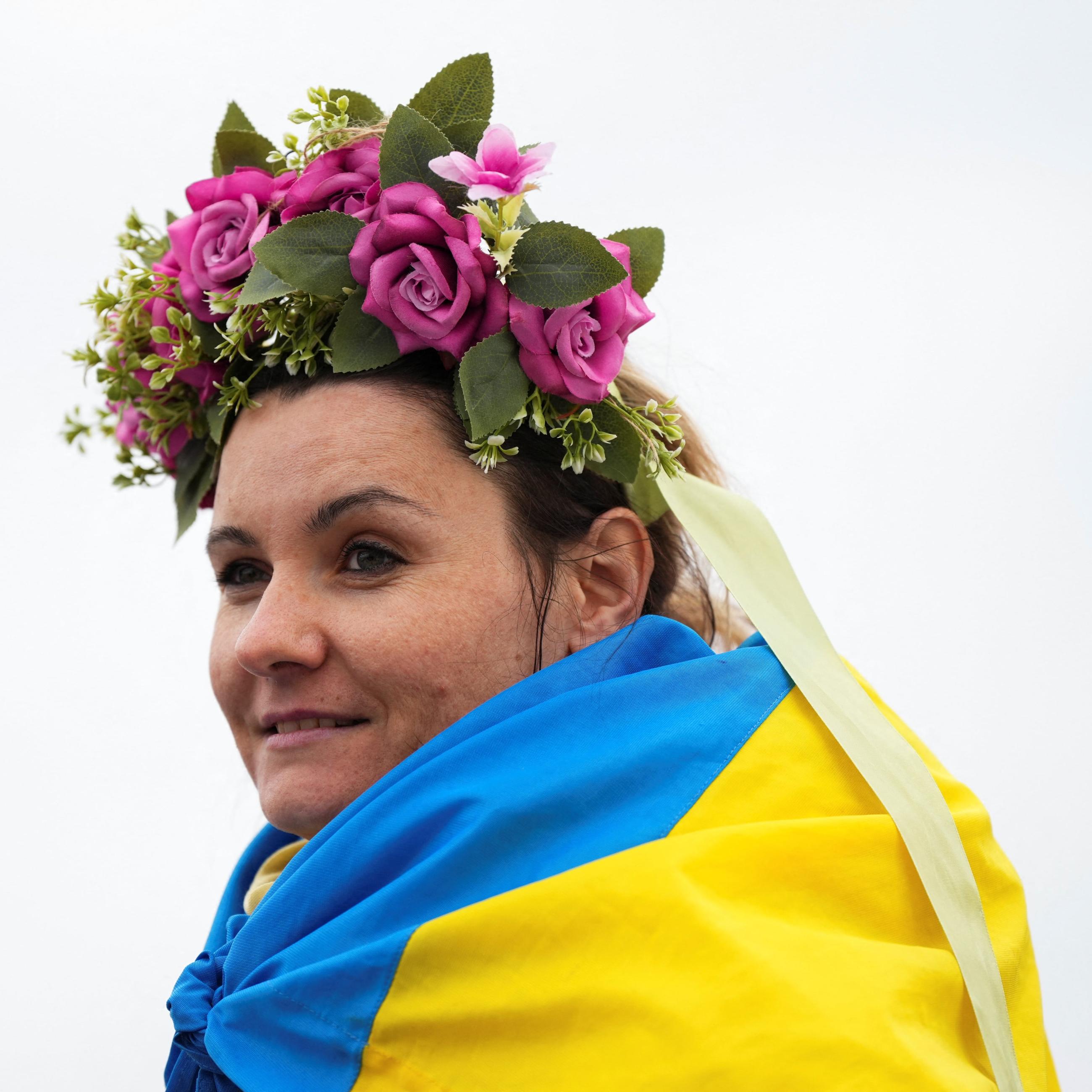 A woman wearing a Ukrainian flag awaits Ukrainian President Volodymyr Zelenskiy, in Warsaw, Poland