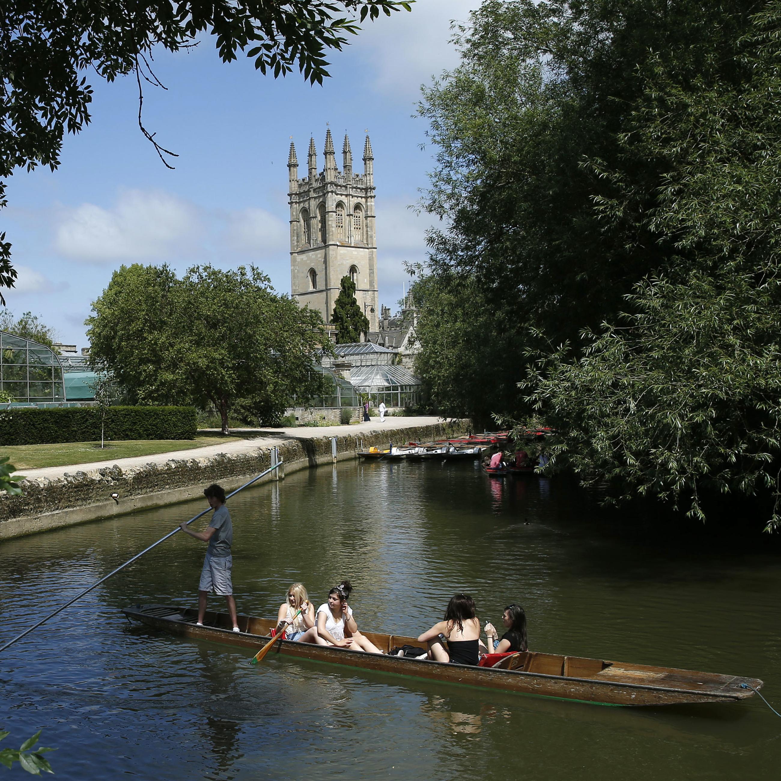 People punt on the river Cherwell past Magdalen College Tower in Oxford, southern England