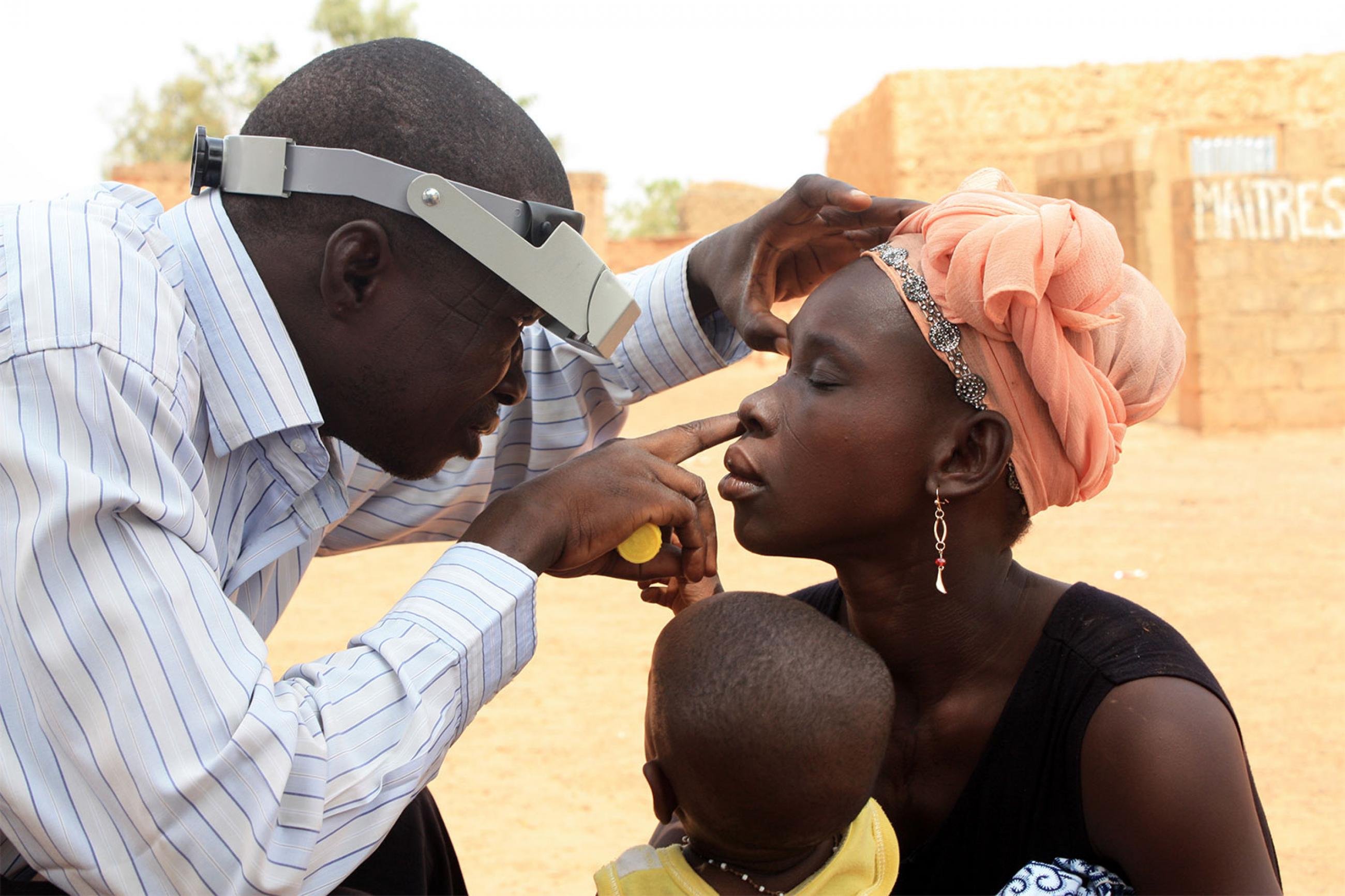 Technician doing eye exam during azithromycin mass drug administration training exercise near Ouagadougou, Burkina Faso.