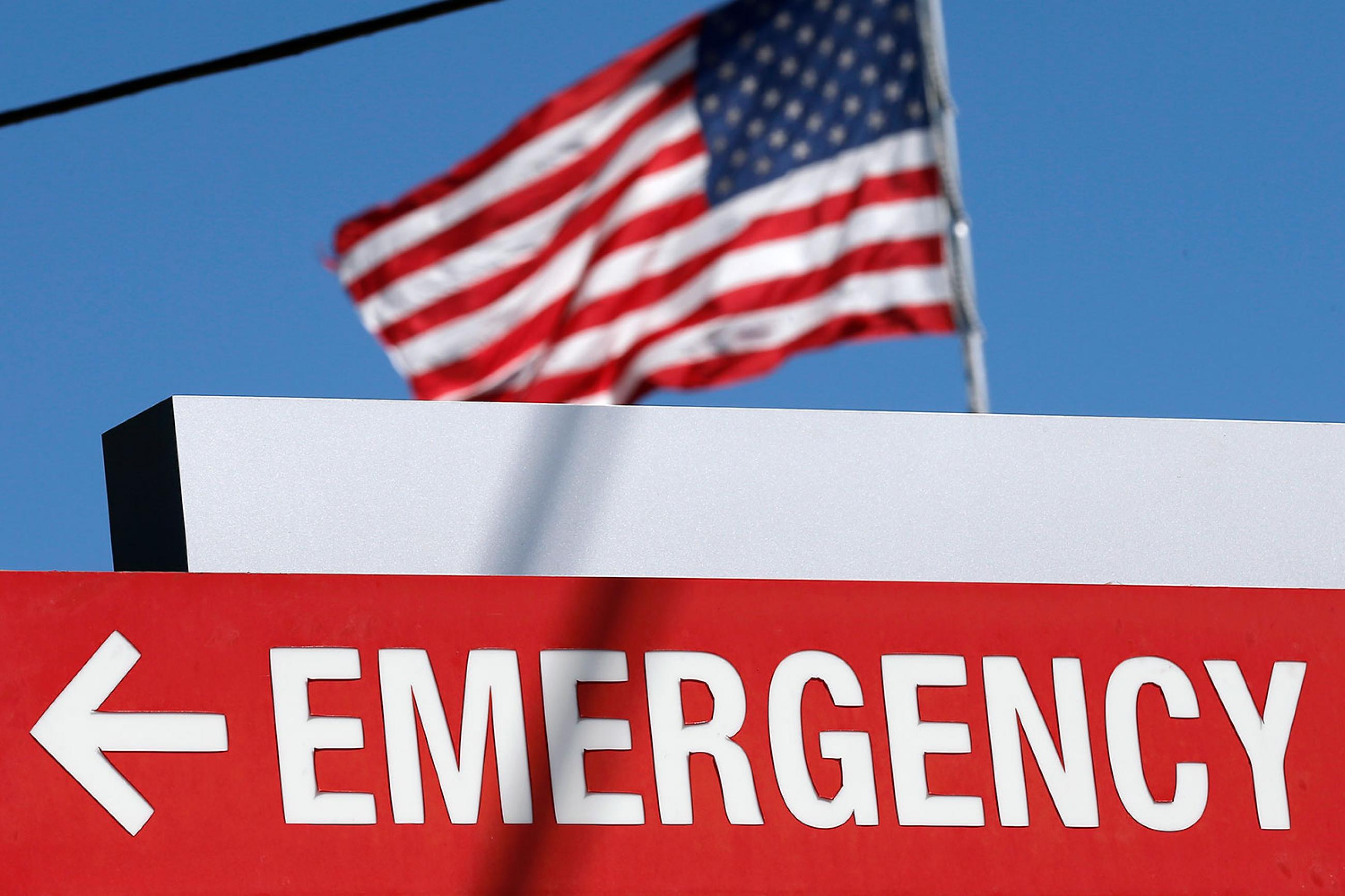 An entrance sign to the Texas Health Presbyterian Hospital in Dallas, Texas, on October 4, 2014. The sign says “EMERGENCY” and points to the left. In the background we can see an American flag billowing against a brilliant clear blue sky. REUTERS/Jim Young